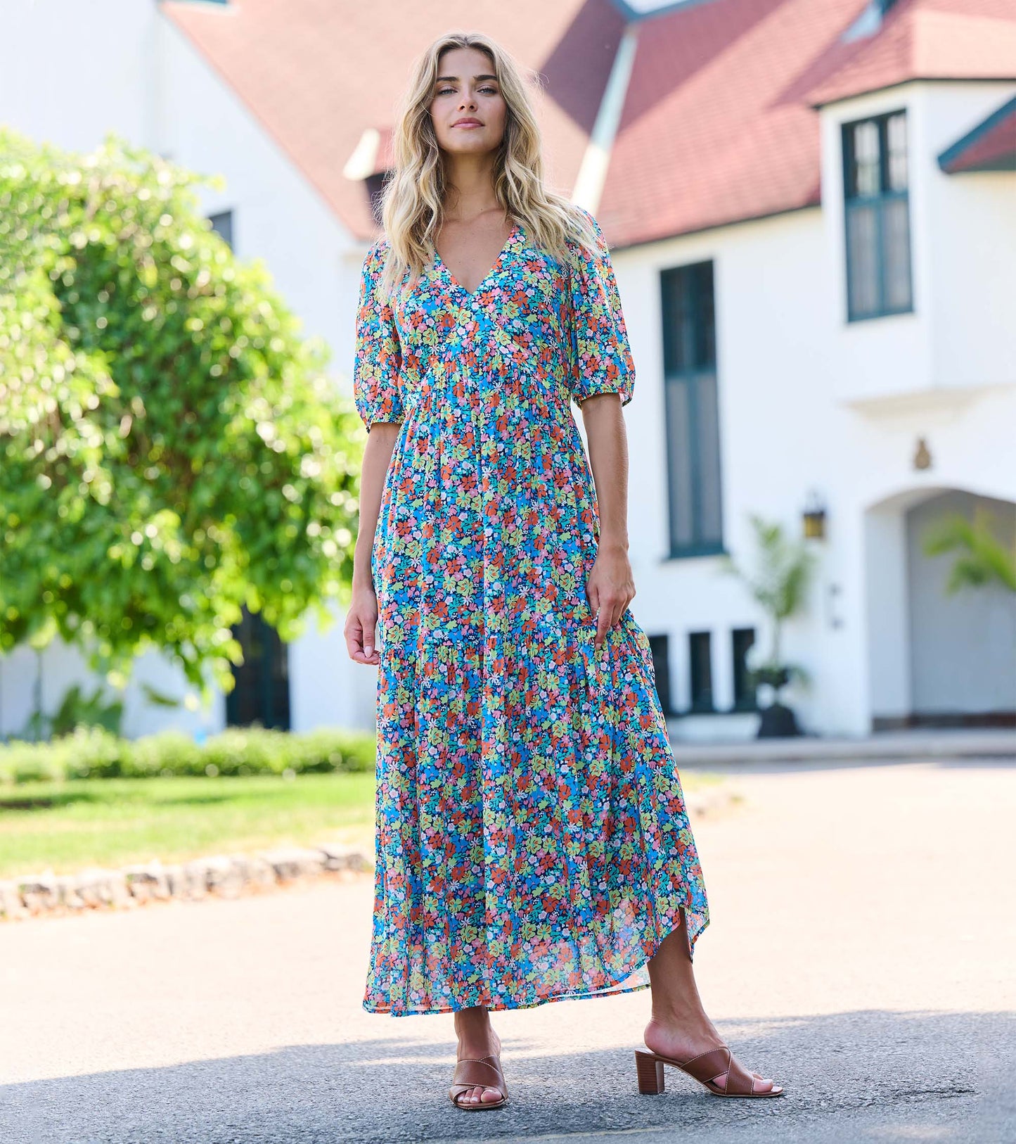 Maxi dress featuring a vibrant floral pattern with puff sleeves and a v-neckline, styled with heeled sandals.
