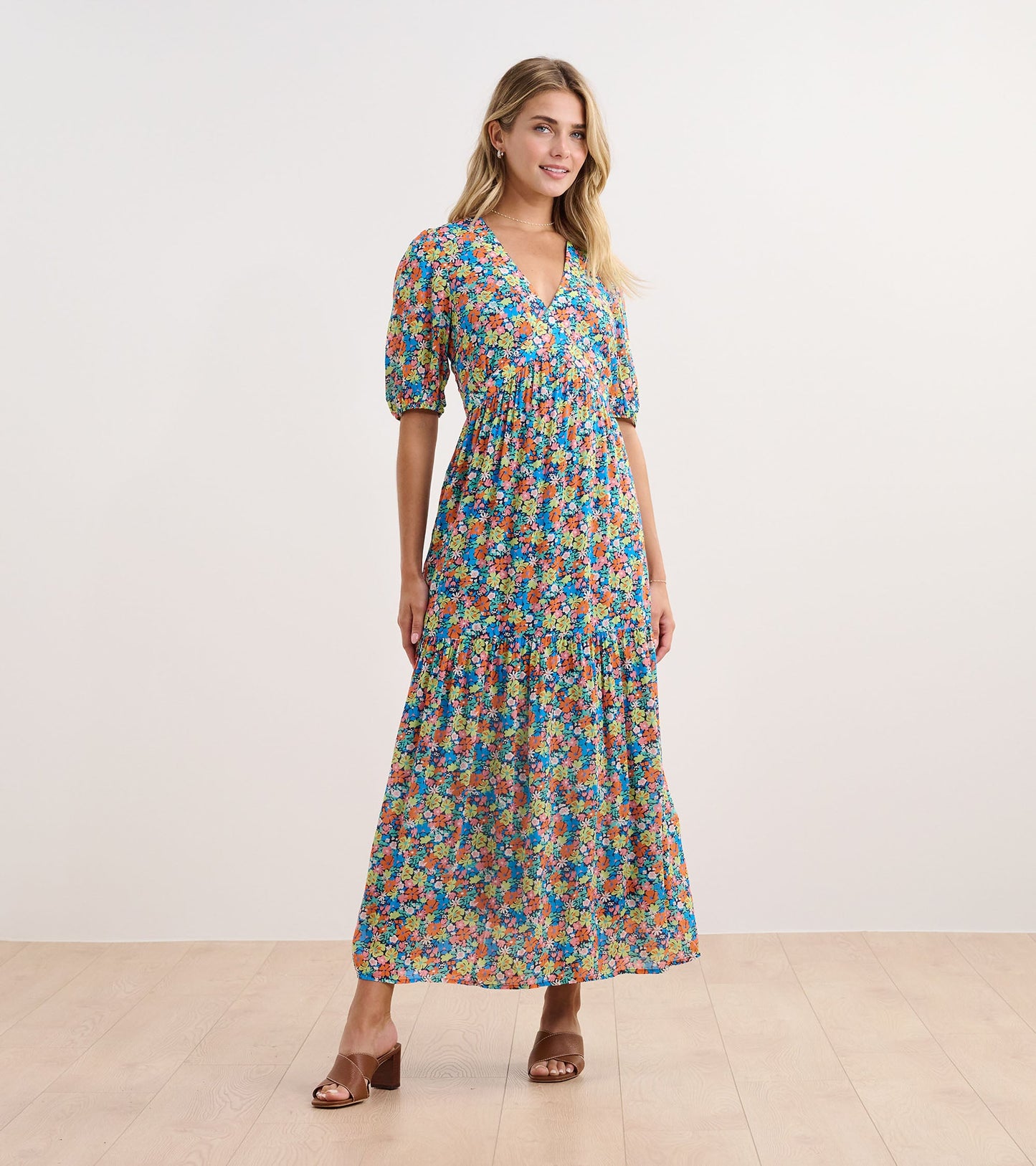 Maxi dress featuring a vibrant floral pattern in blue, orange, and green with a V-neck and puff sleeves.