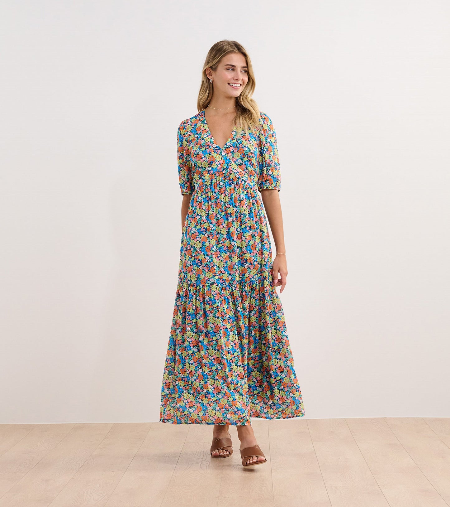 Maxi dress featuring a vibrant floral pattern in blue, orange, and green with short puff sleeves and a V-neckline.
