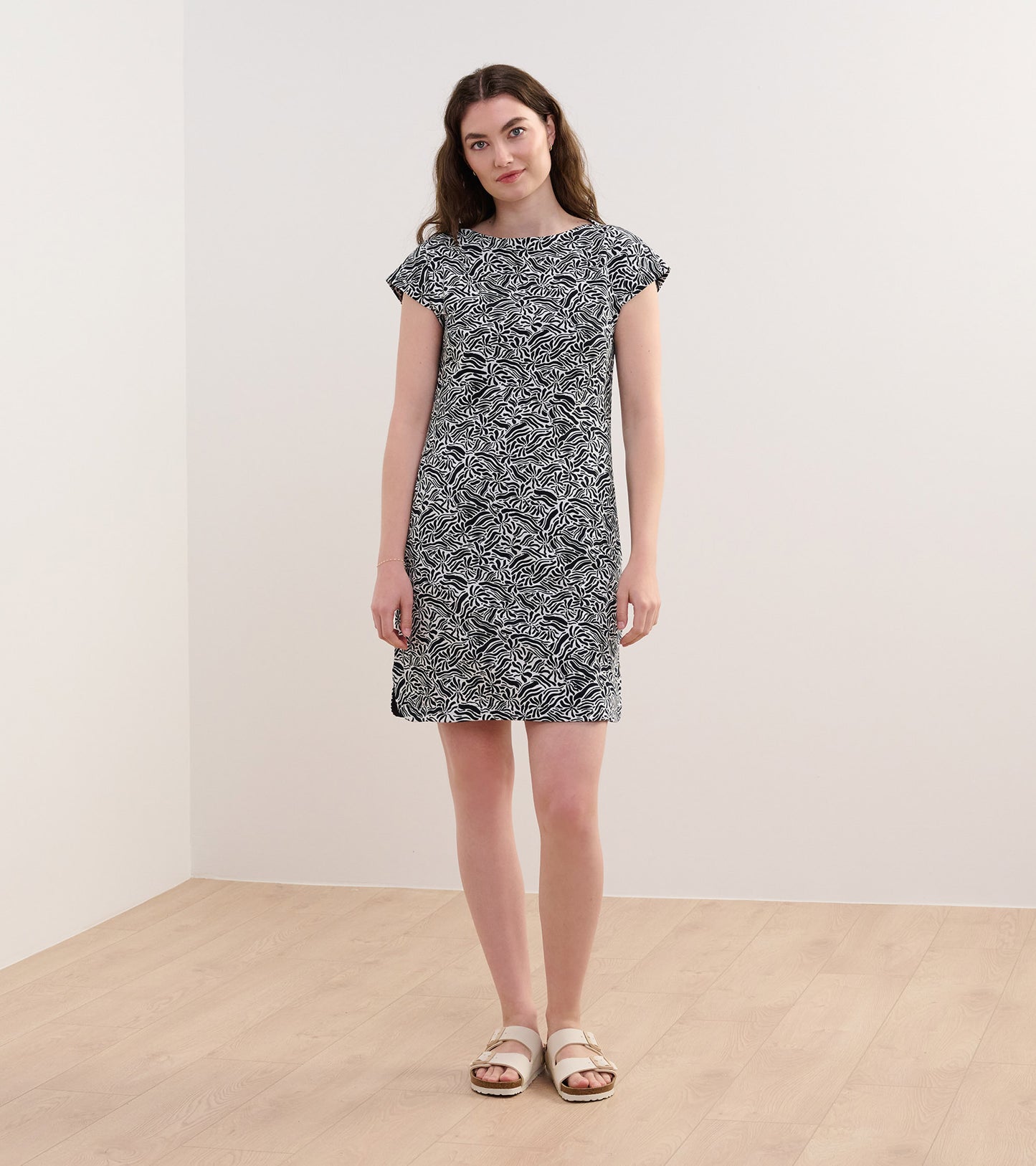 Black and white short-sleeve dress featuring a groovy floral pattern, knee-length cut, and relaxed fit.