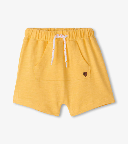 Golden cream kangaroo shorts with an elastic waistband and front pockets, featuring a drawstring and logo patch.