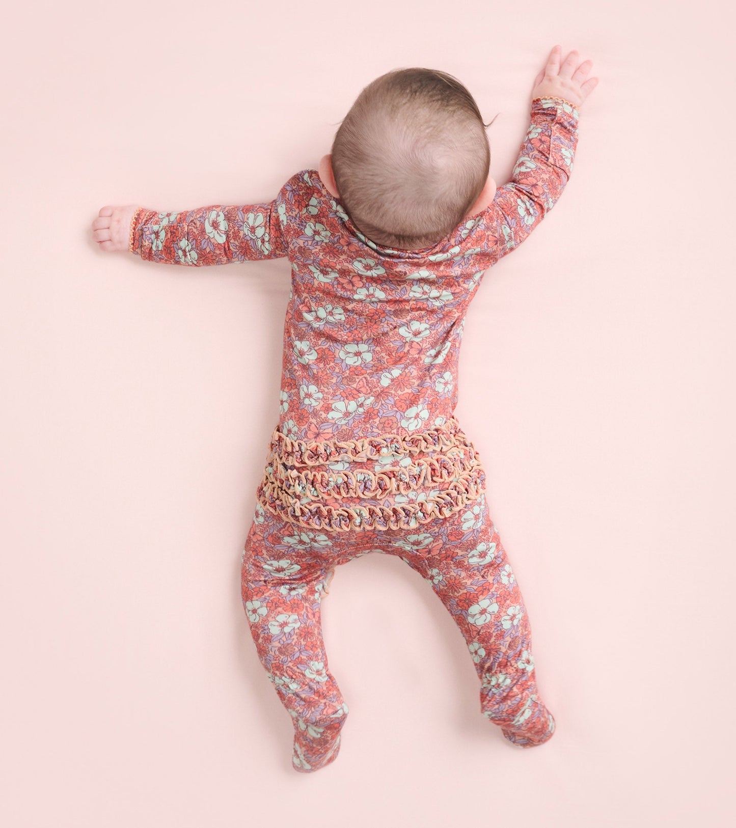 Floral-patterned footed sleeper in pink and blue, designed for baby girls, featuring long sleeves and a snug fit.