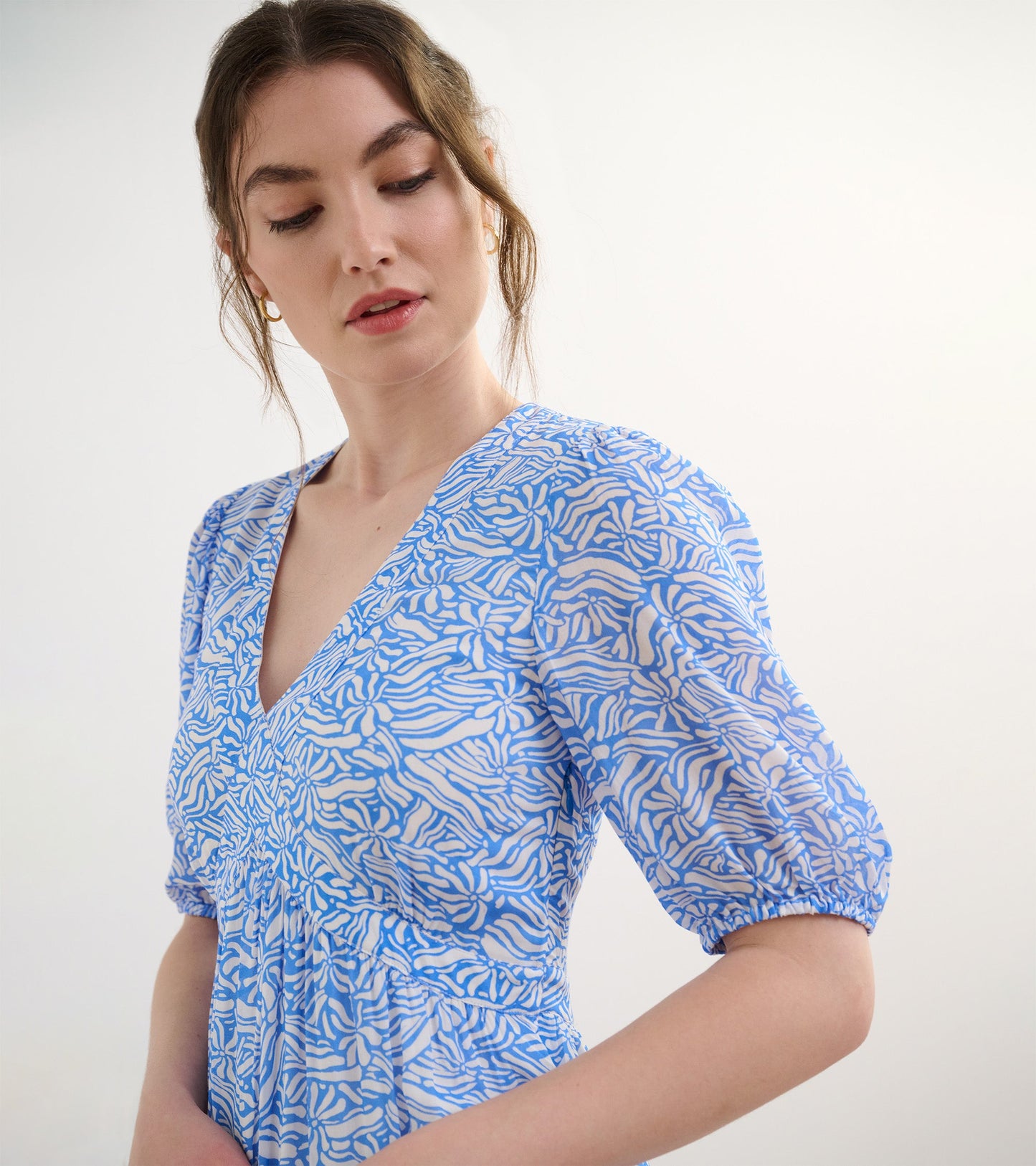 Light blue dress featuring a groovy floral pattern, with a V-neckline and puff sleeves.