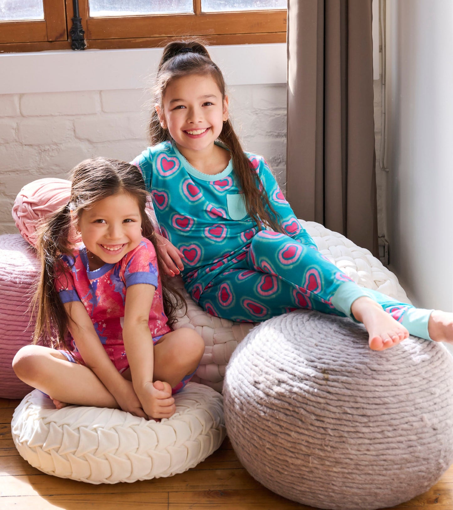 Turquoise pajama set with glowing hearts pattern, paired with a pink and purple short-sleeve outfit, worn by two girls.