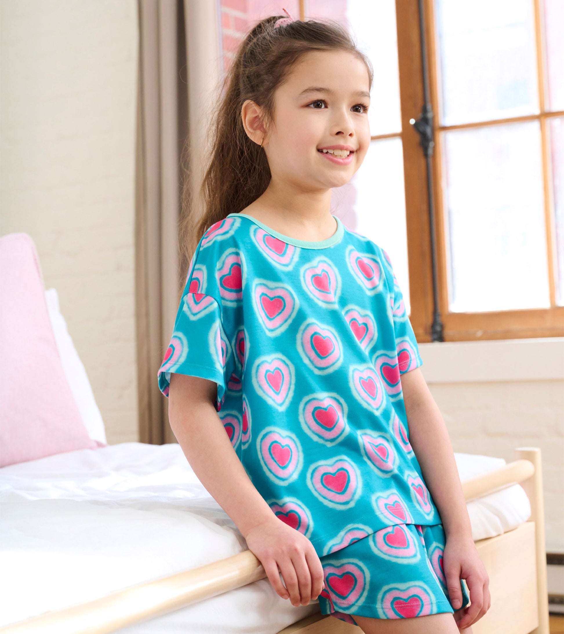 Turquoise pajama set featuring pink glowing hearts, short sleeves, and matching shorts, ideal for girls.