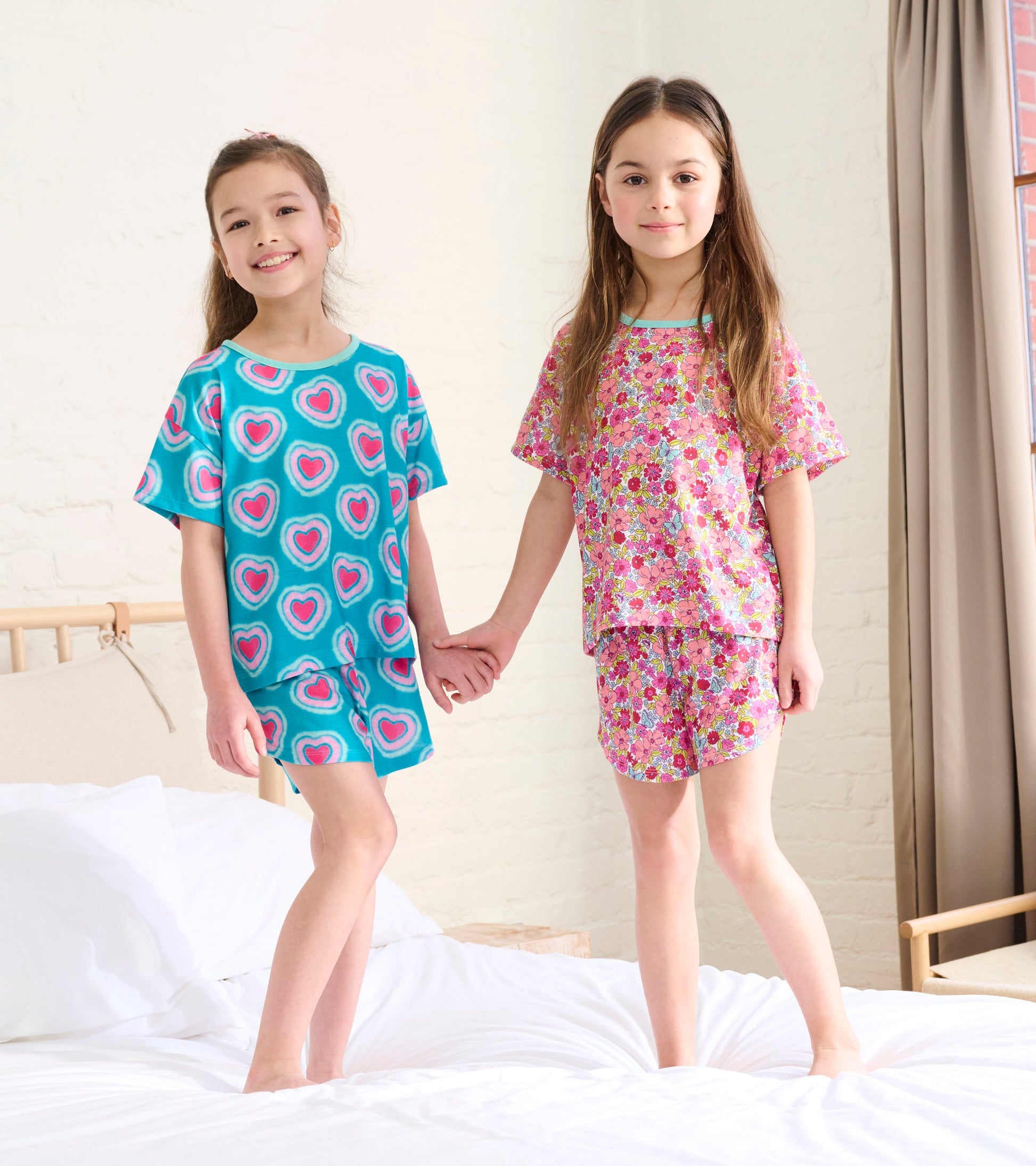 Girls' pajama set featuring a turquoise top with heart patterns and a pink floral design on the shorts, perfect for sleepwea…
