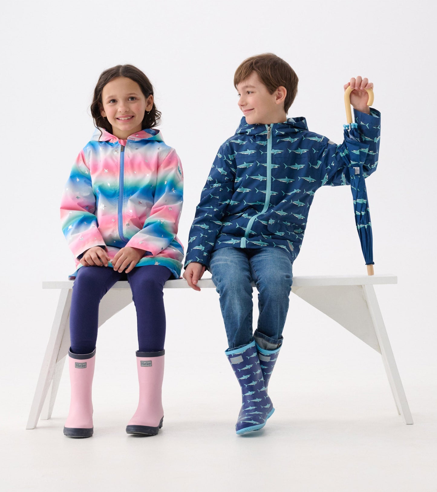 Colorful A-line swing jacket with glitter stars, worn by a girl, paired with a blue shark-patterned jacket on a boy.