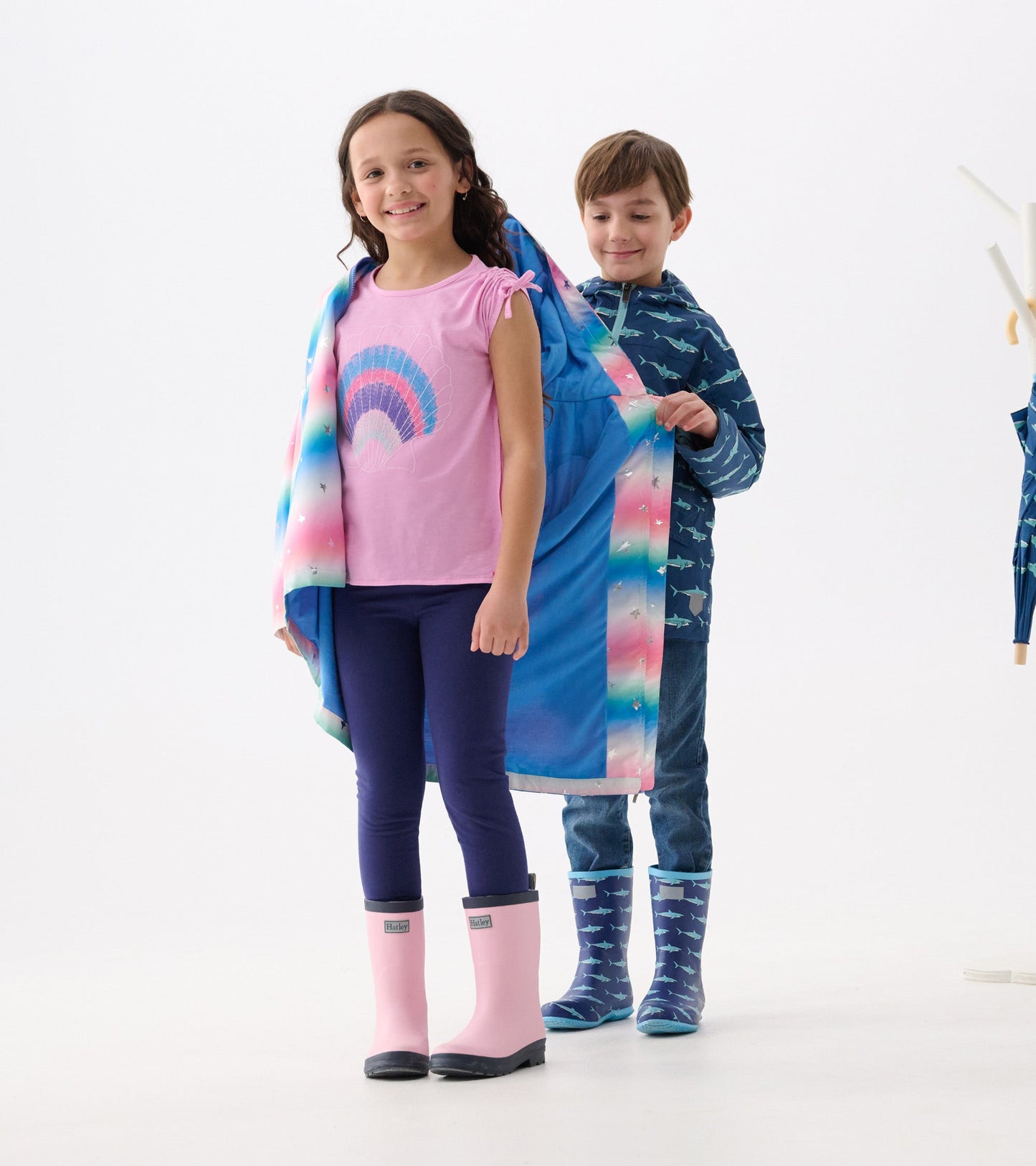 A girl in a pink top and leggings wears a colorful glitter star A-line swing jacket, while a boy stands behind her.