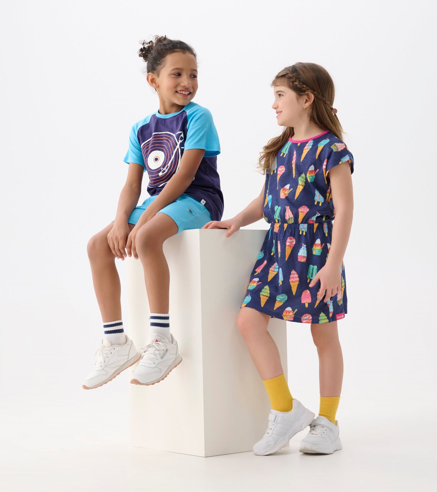 Navy dress with colorful ice cream cone pattern, relaxed fit, short sleeves, and elastic waist, worn by a girl.