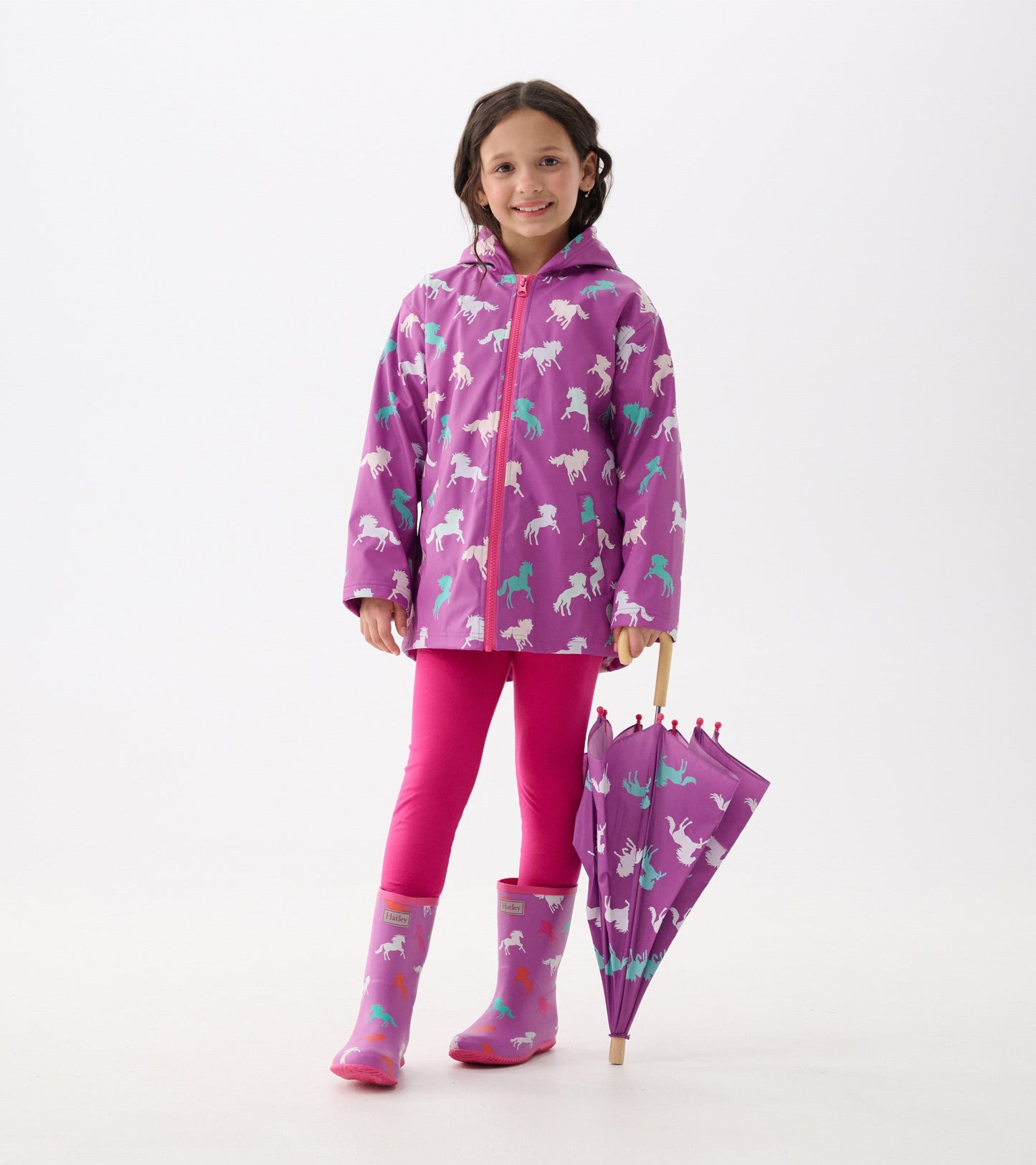 Purple zip-up rain jacket featuring leaping horses, paired with pink leggings and matching umbrella.
