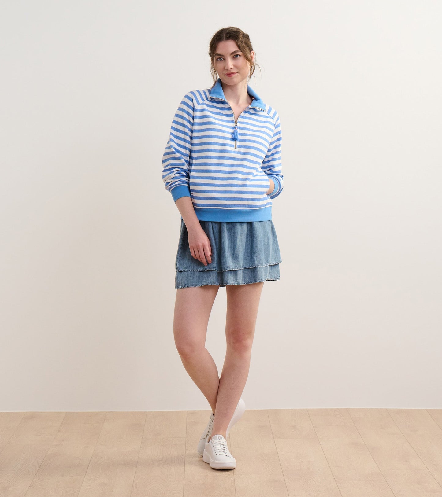 Blue and white striped mock neck pullover with a zip front, paired with a denim skirt and white sneakers.