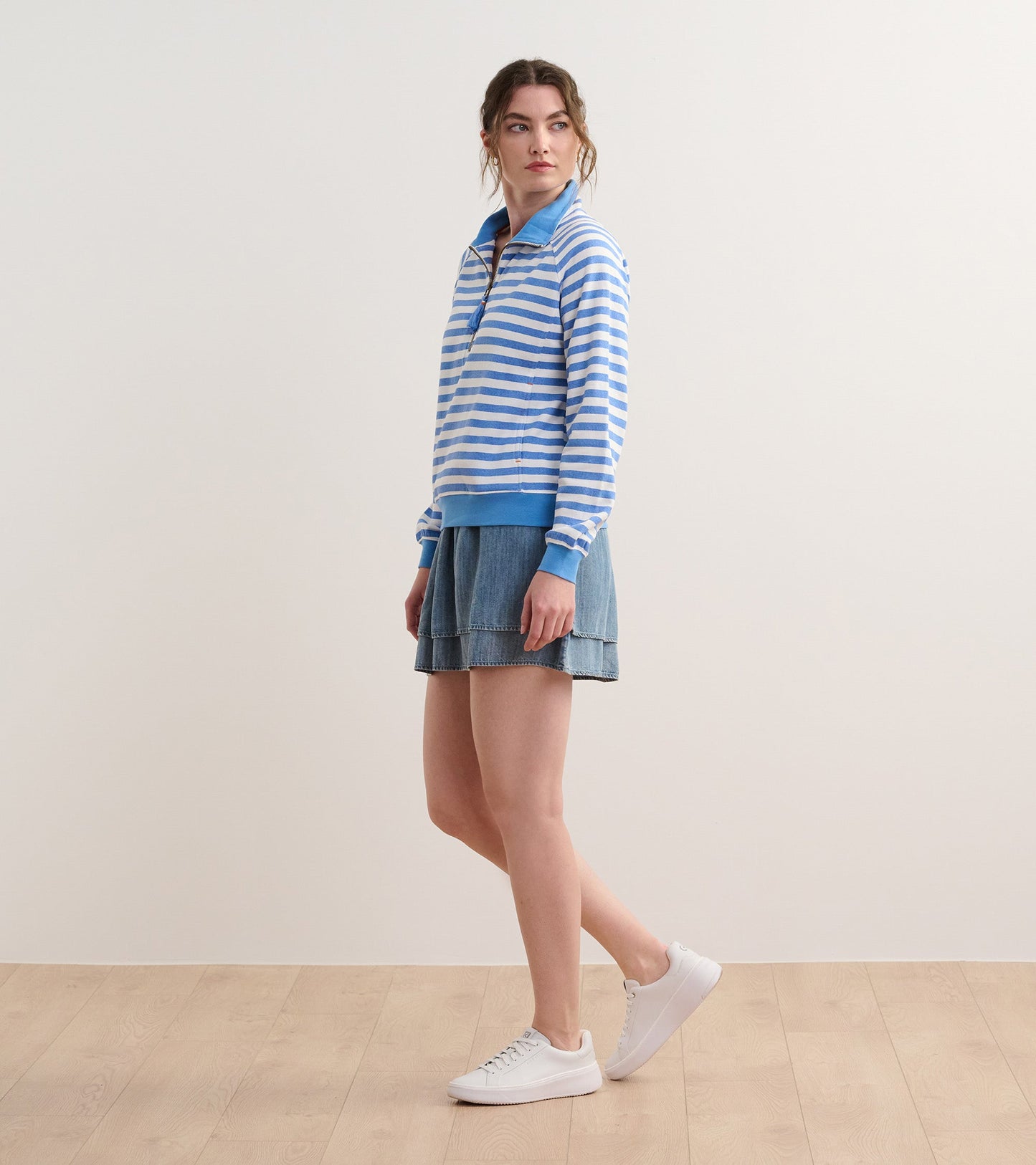 Blue and white striped mock neck pullover, featuring a zip front and ribbed cuffs, paired with a denim skirt.