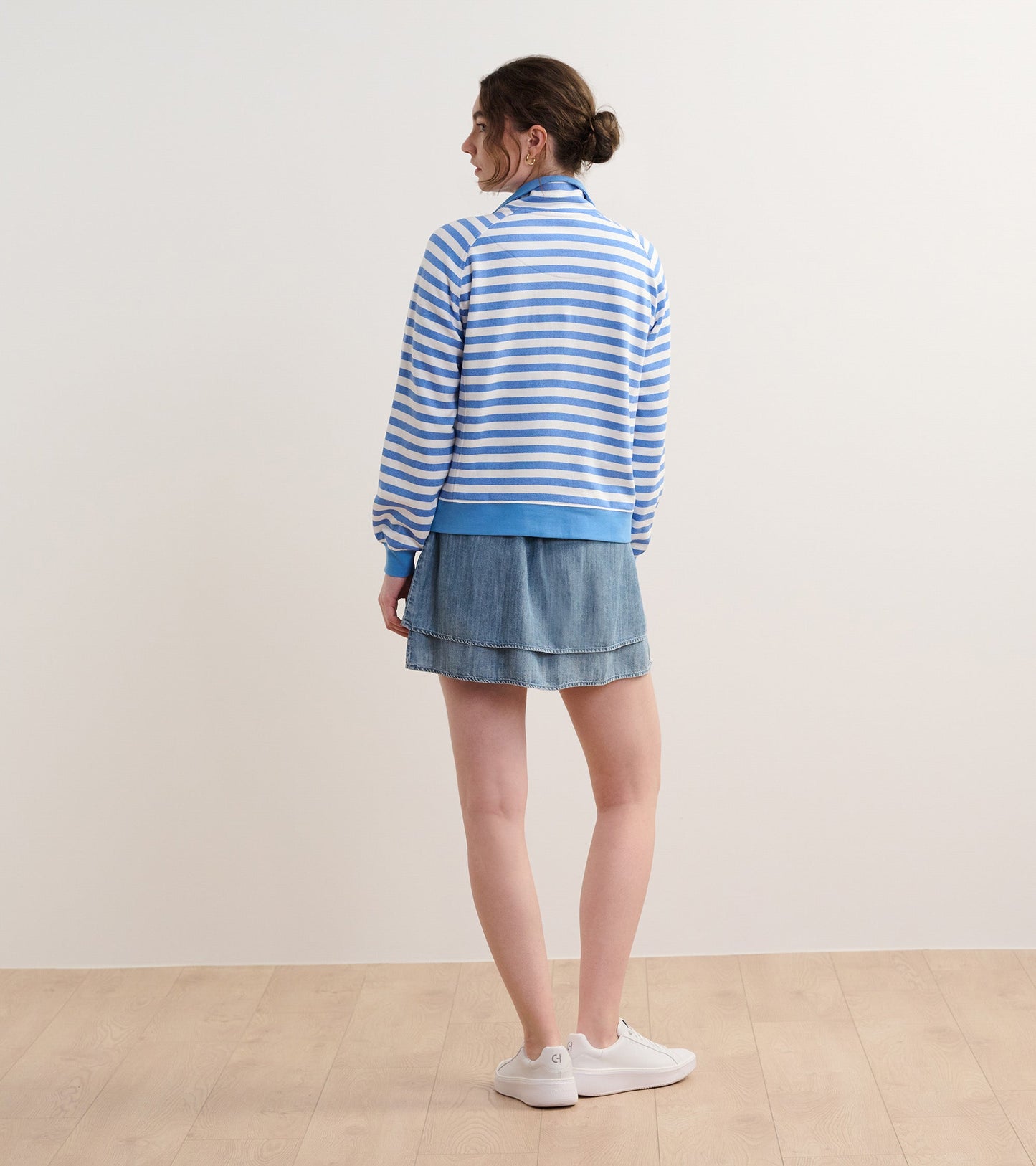 Blue and white striped mock neck pullover, featuring long sleeves, paired with a denim skirt and white sneakers.