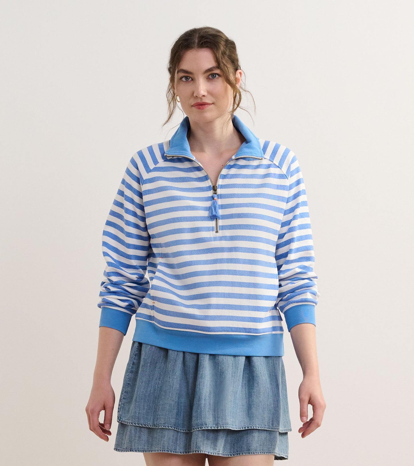 Light blue mock neck pullover with white stripes and a zip front, paired with a denim skirt.