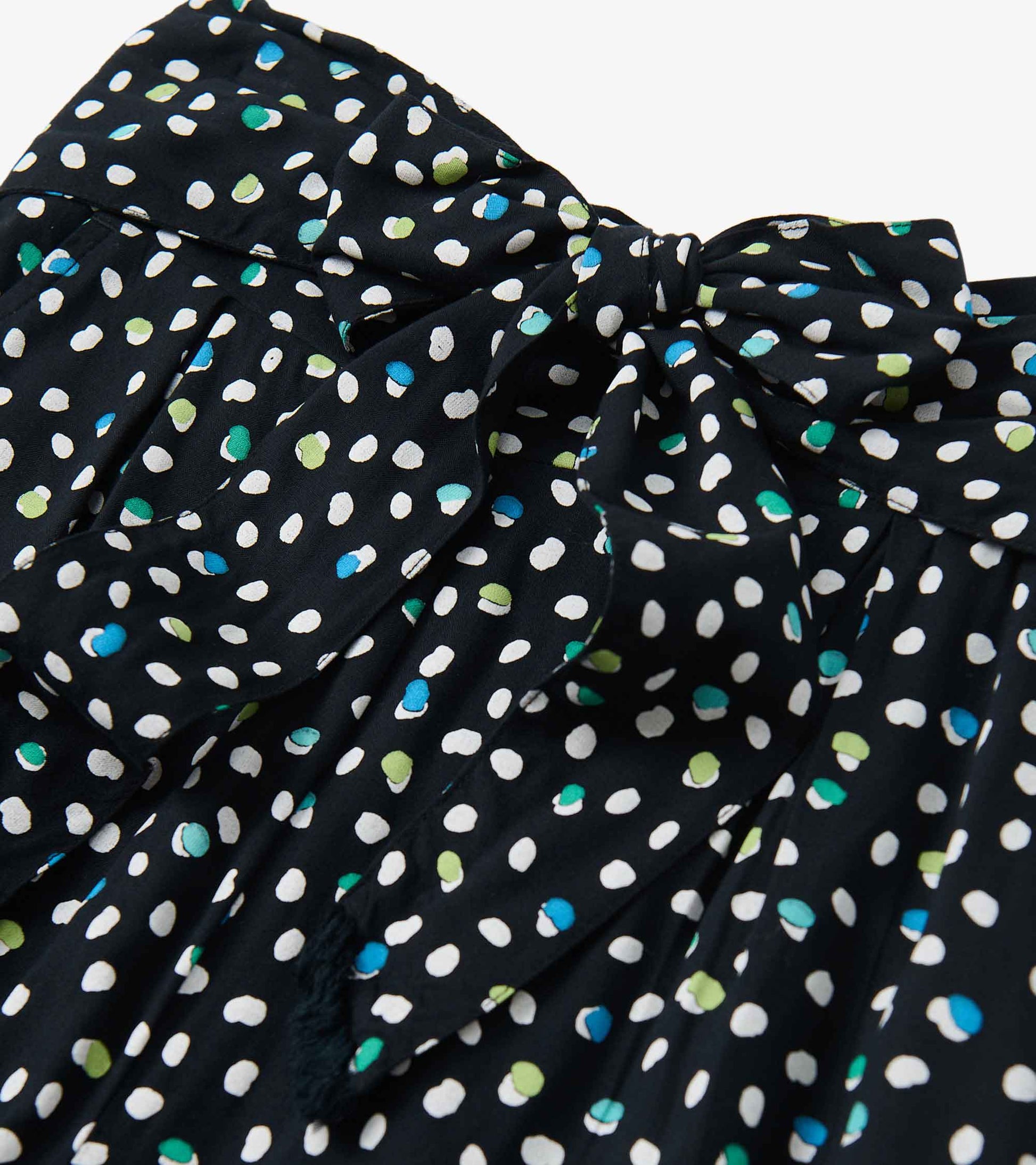 Belted wide leg pants featuring a black fabric with multi-colored polka dots and a tied waist detail.