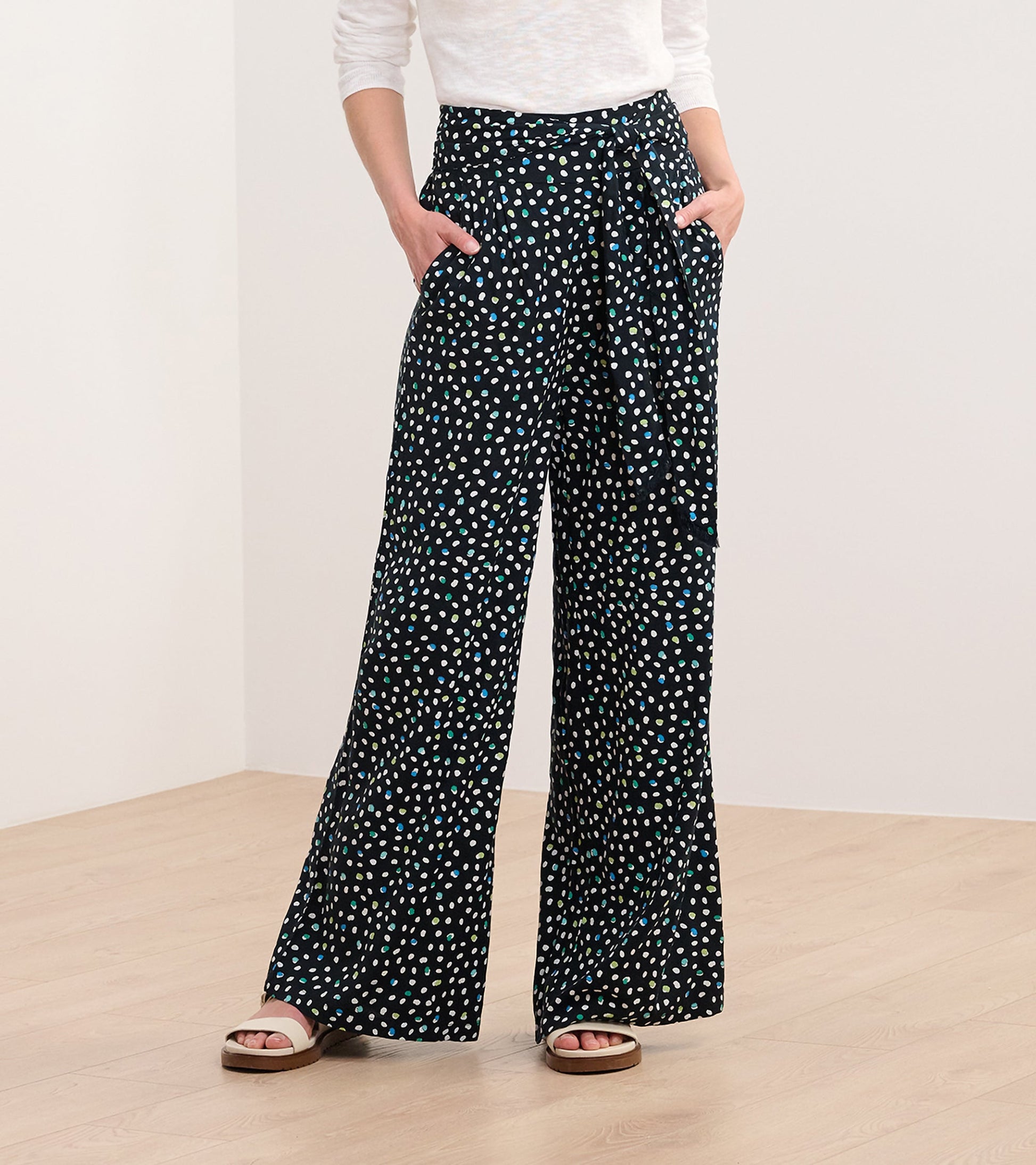 Belted wide leg pants in black with a multi-dot pattern, featuring side pockets and a tied waist detail.