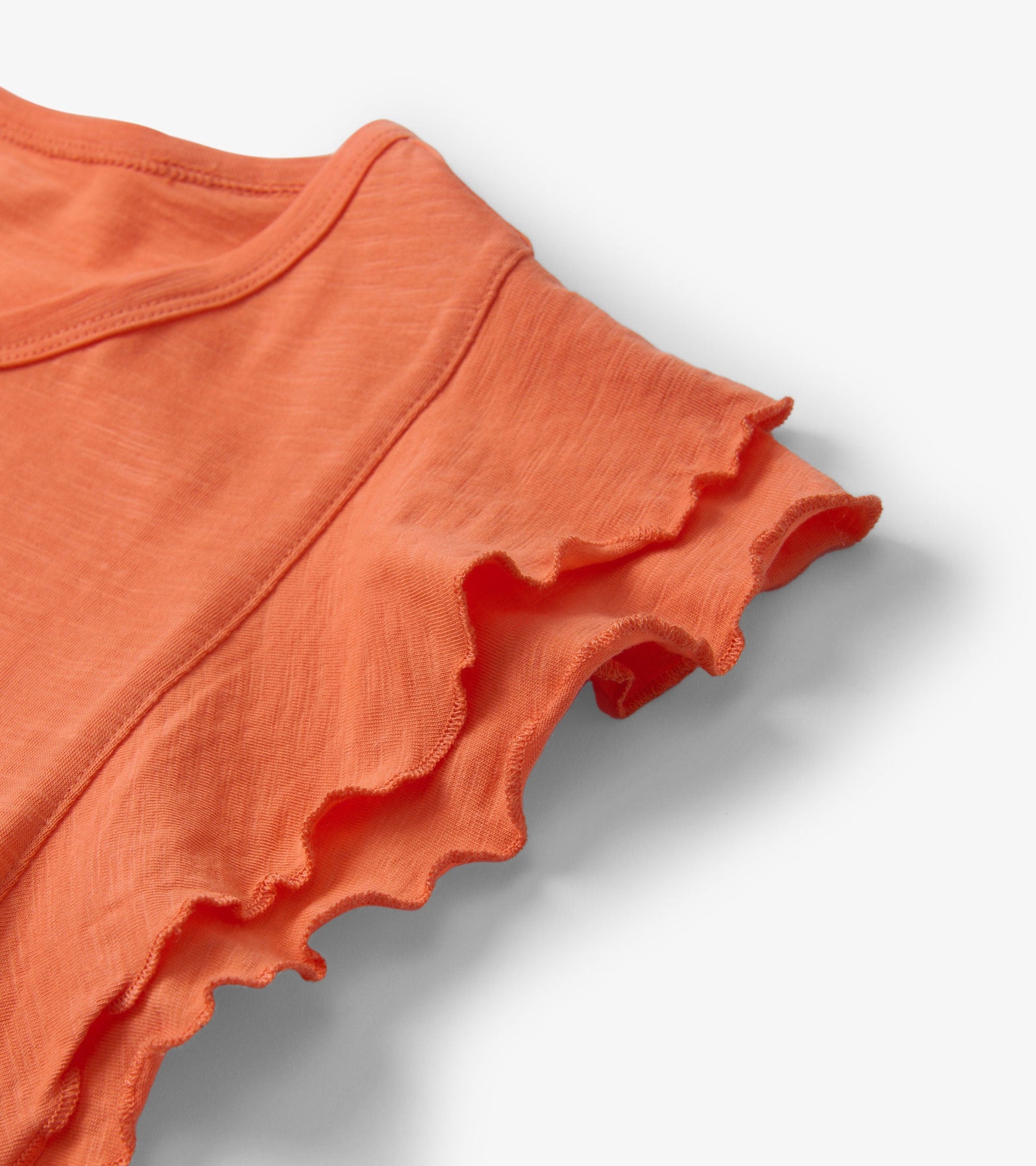 Melon-colored tank top featuring layered ruffle sleeves and a soft, lightweight fabric.