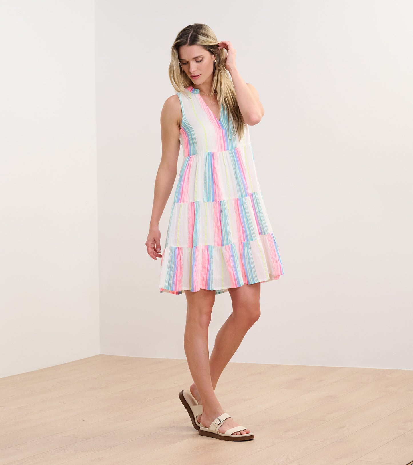 Sleeveless dress with a tiered design featuring neon bright stripes in pink, blue, and yellow on a light background.