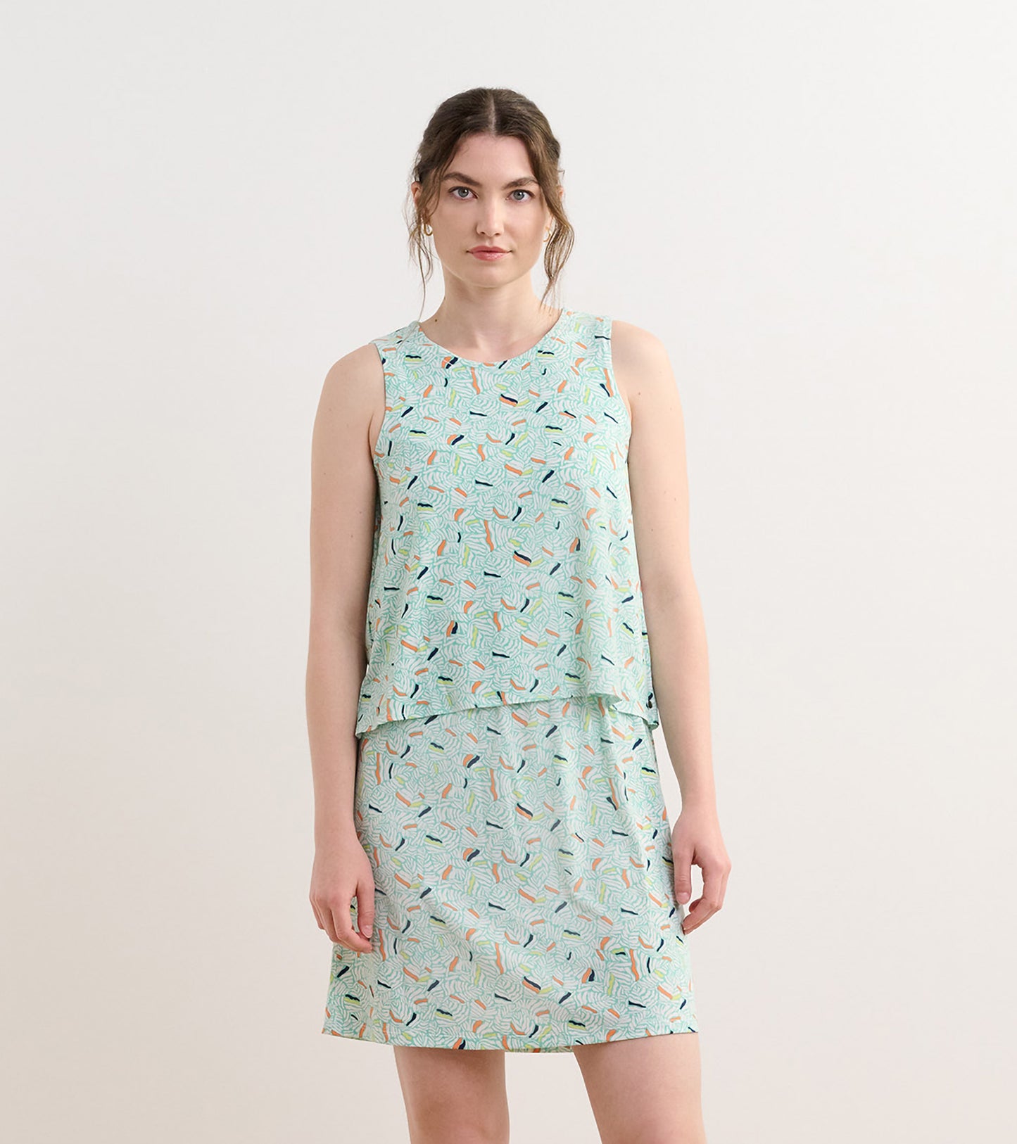 Light green sleeveless dress with a layered design and a leaf pattern in various colors.