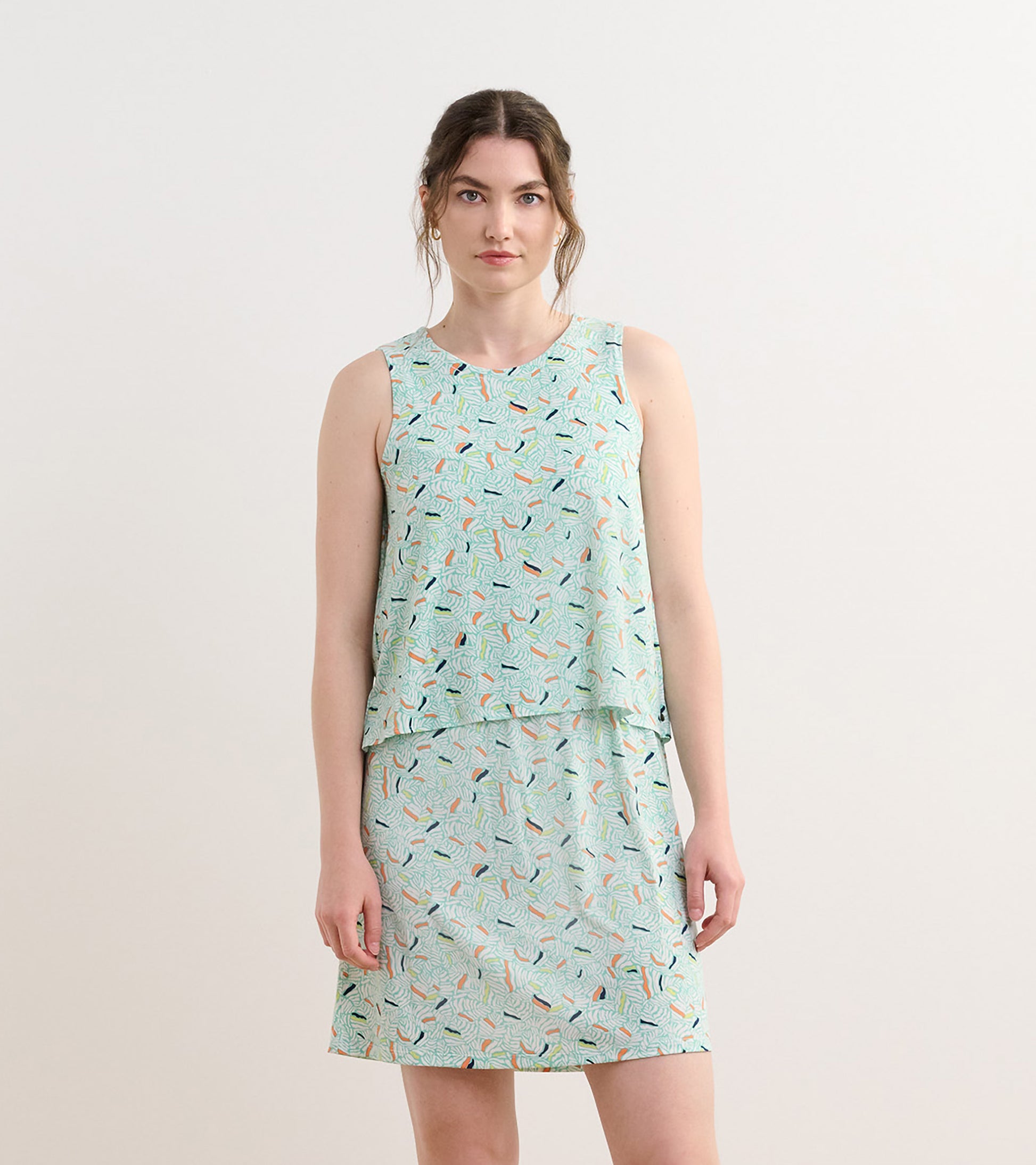 Light green sleeveless dress with a layered design and a leaf pattern in various colors.