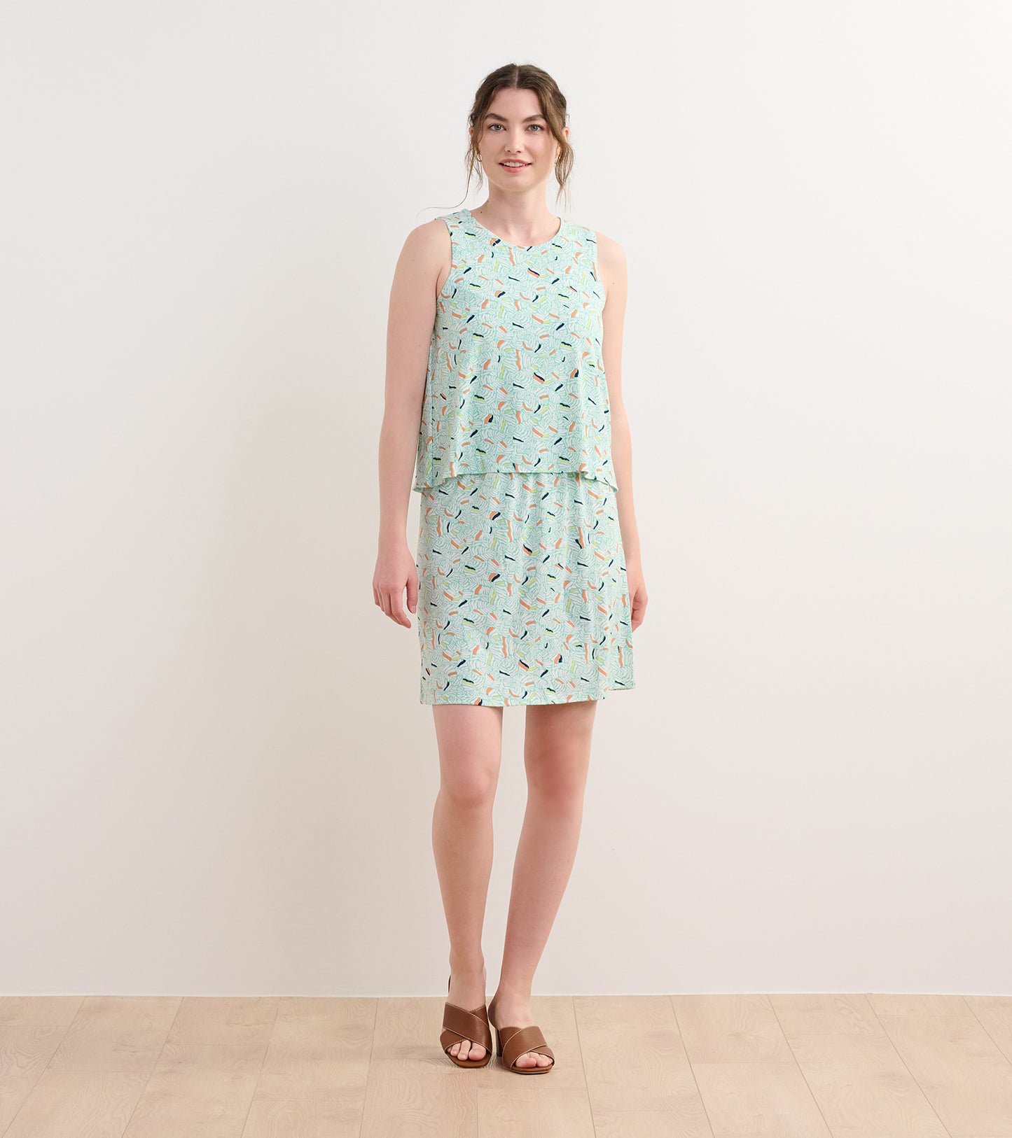 Light green sleeveless dress with a layered design, featuring a colorful organic leaf pattern.