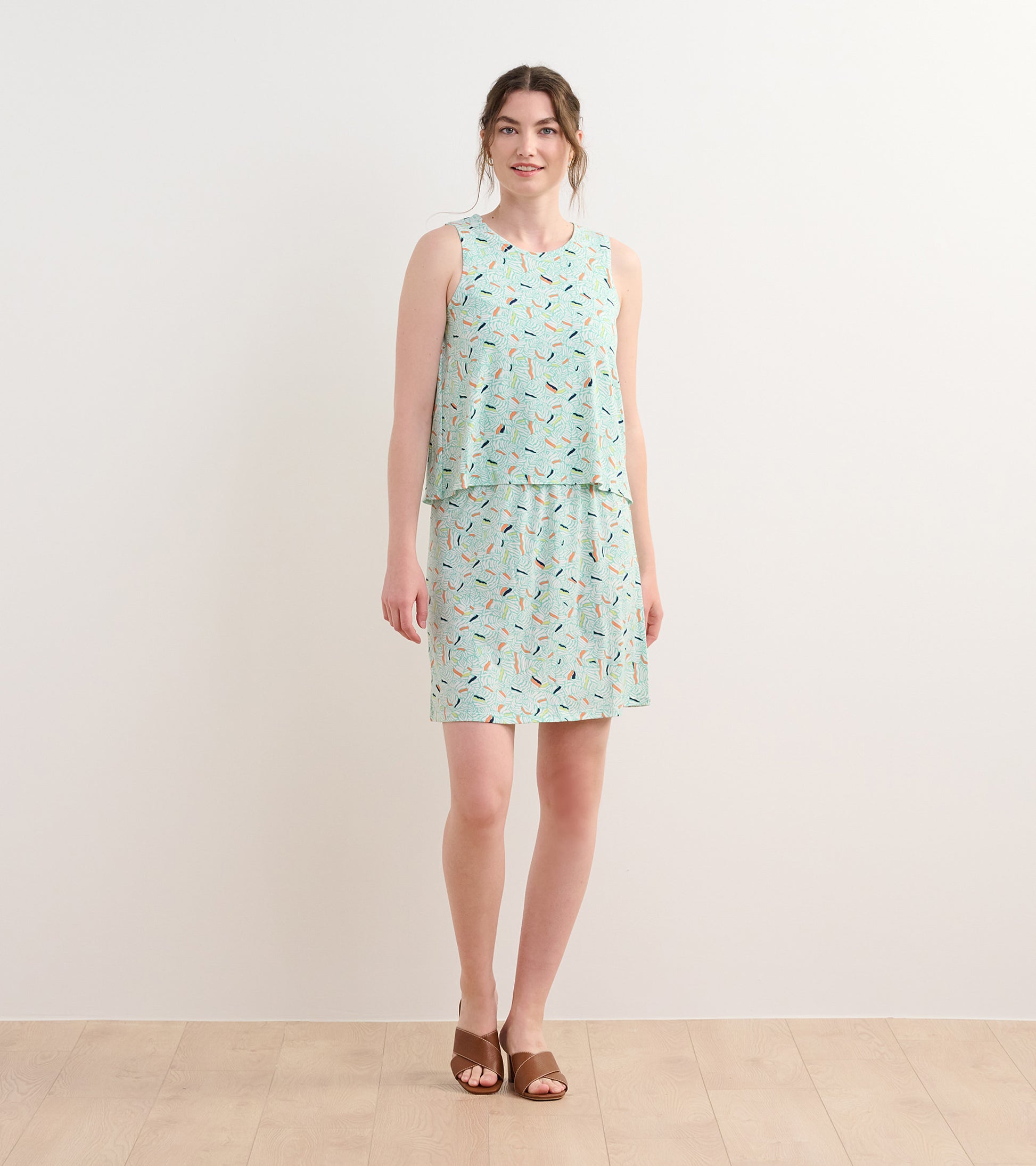 Light green sleeveless dress with a layered design, featuring a colorful organic leaf pattern.