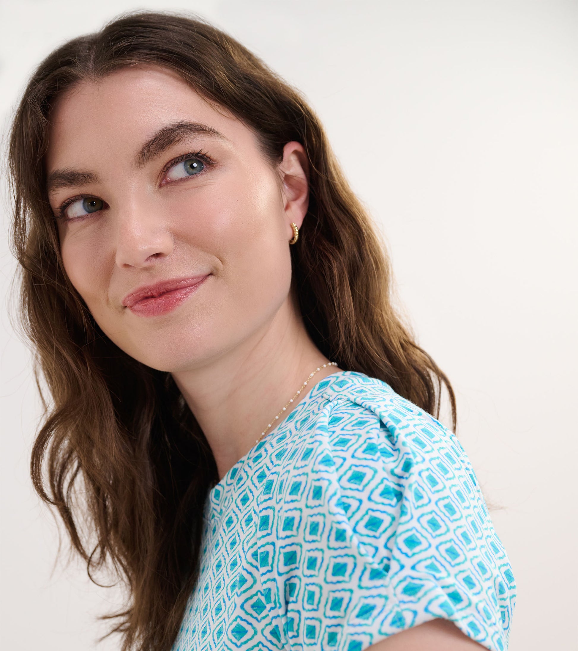 Light blue dress featuring a geometric pattern, short sleeves, and a round neckline, styled with loose waves.