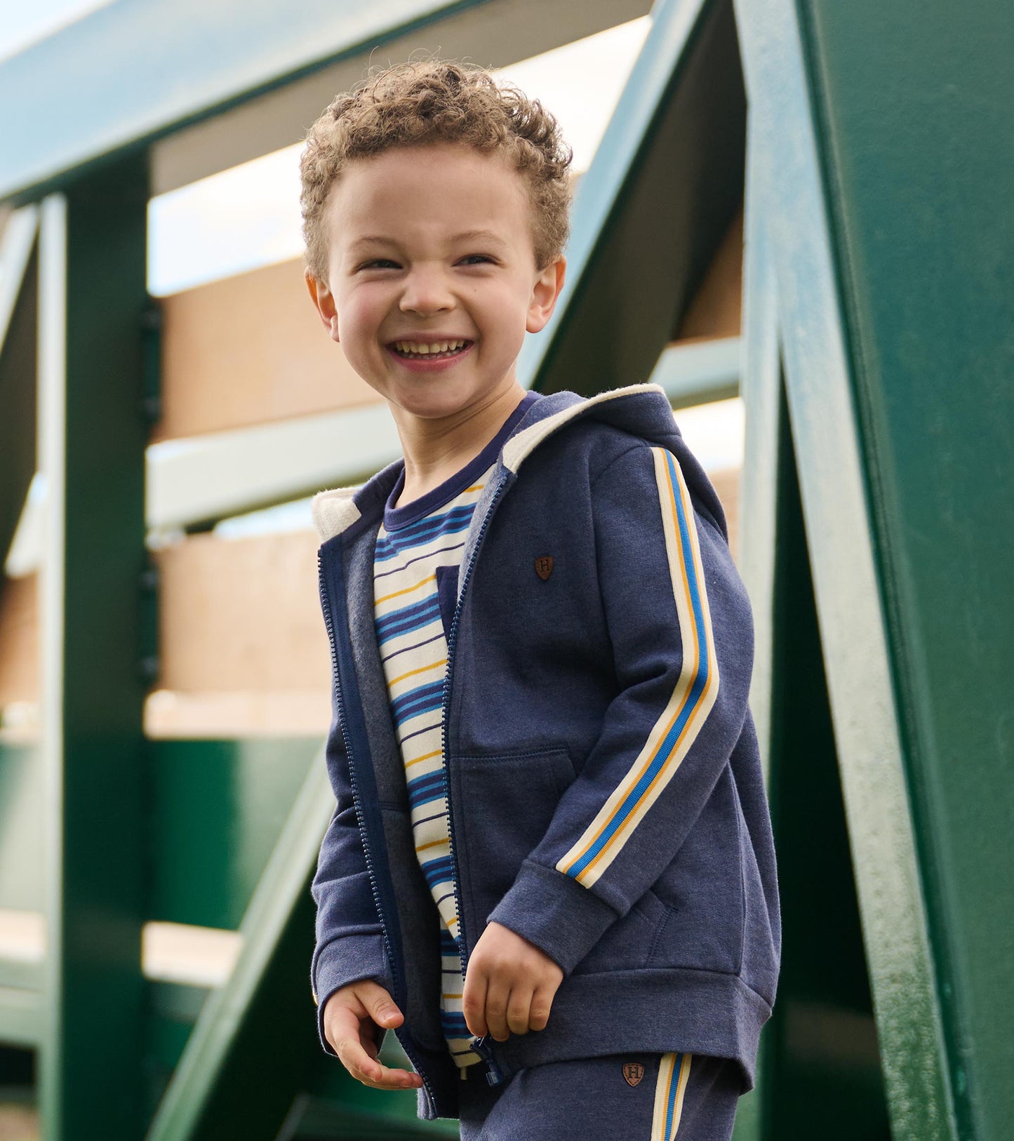 Patriot blue zip-up hoodie with striped sleeves, featuring a front zipper and hood, worn by a smiling child outdoors.