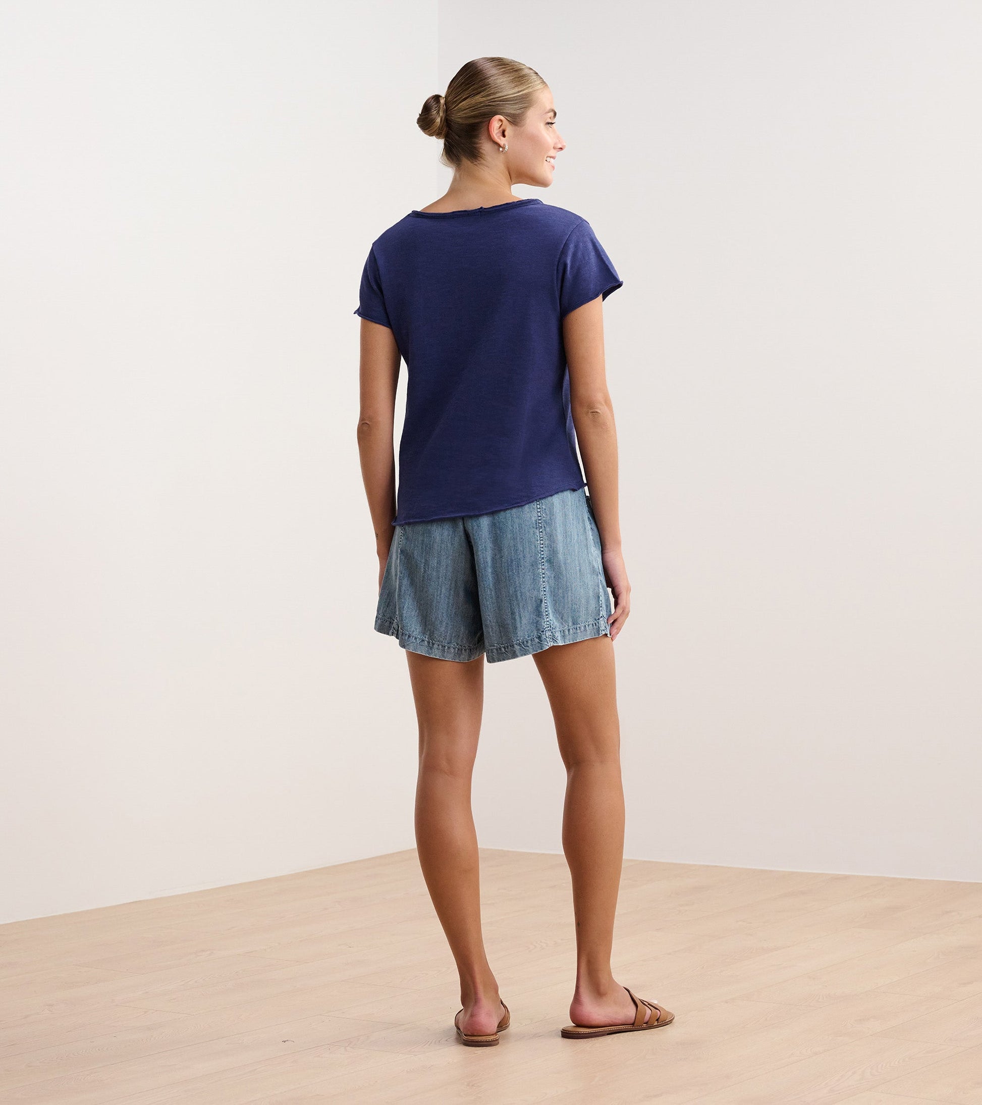 Patriot blue V-neck tee with short sleeves, styled with denim shorts, viewed from the back.