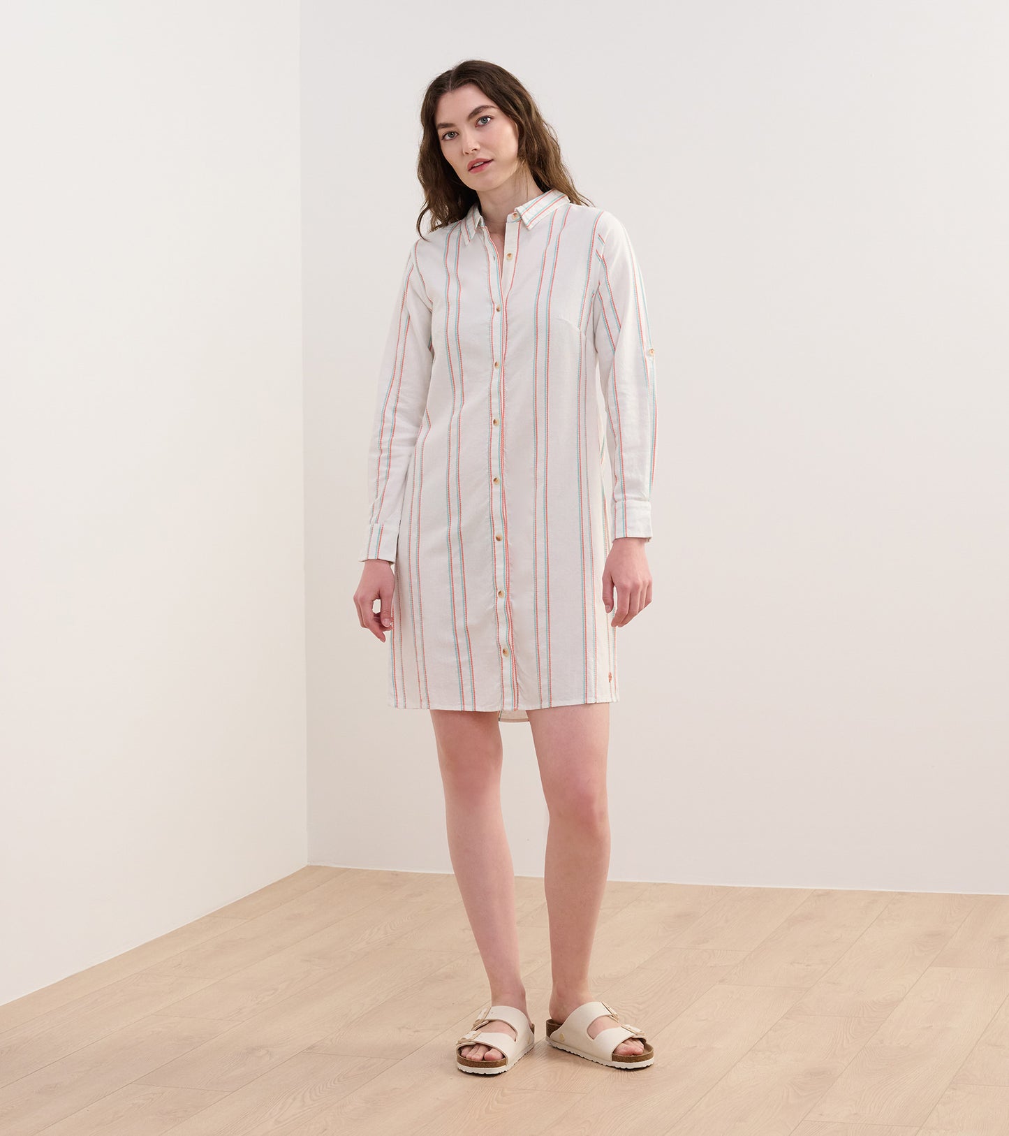 Peach and white striped shirt dress with long sleeves and button front, styled with sandals.