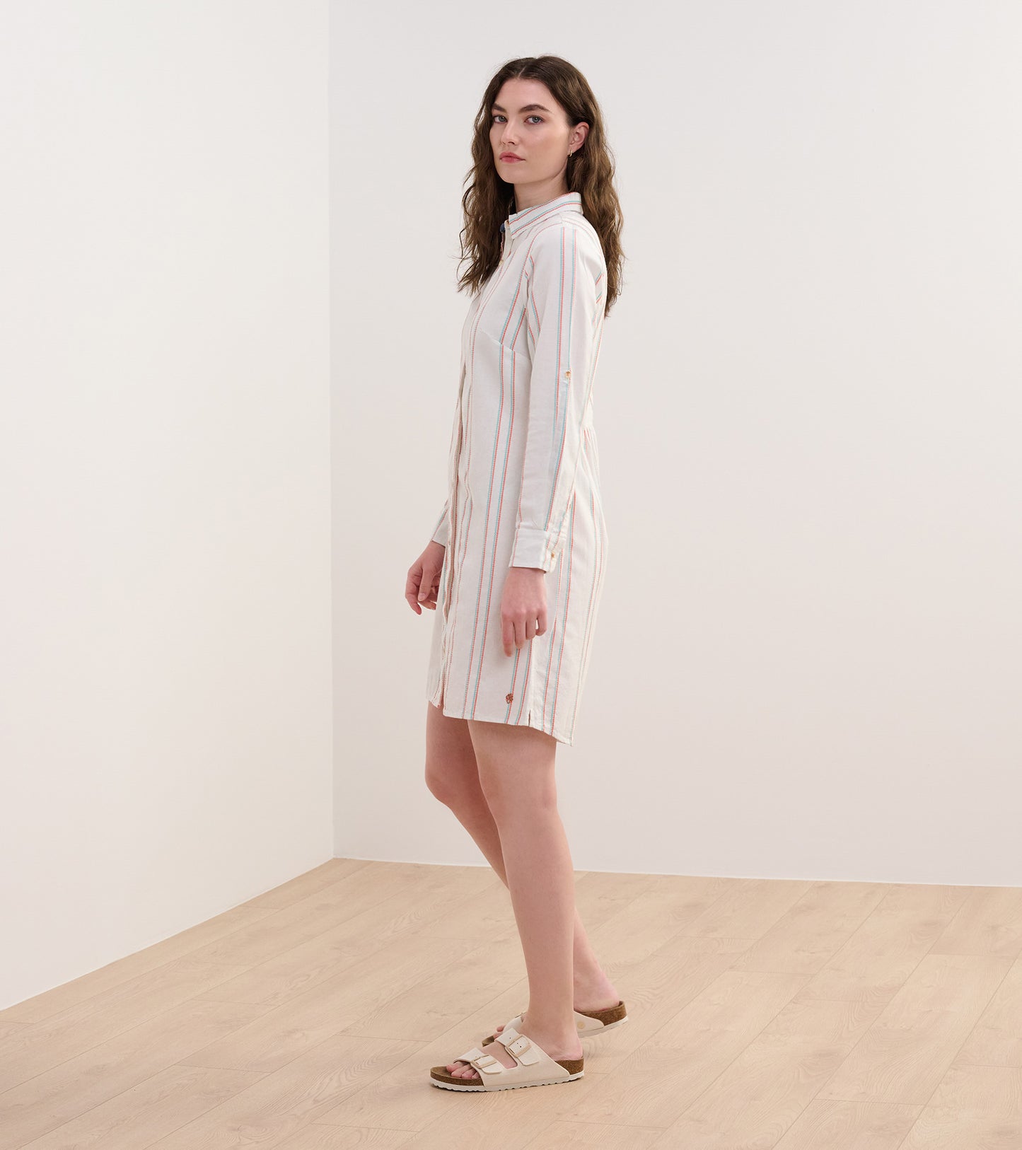 Peach and white striped shirt dress with long sleeves and a button-down front, styled with casual sandals.
