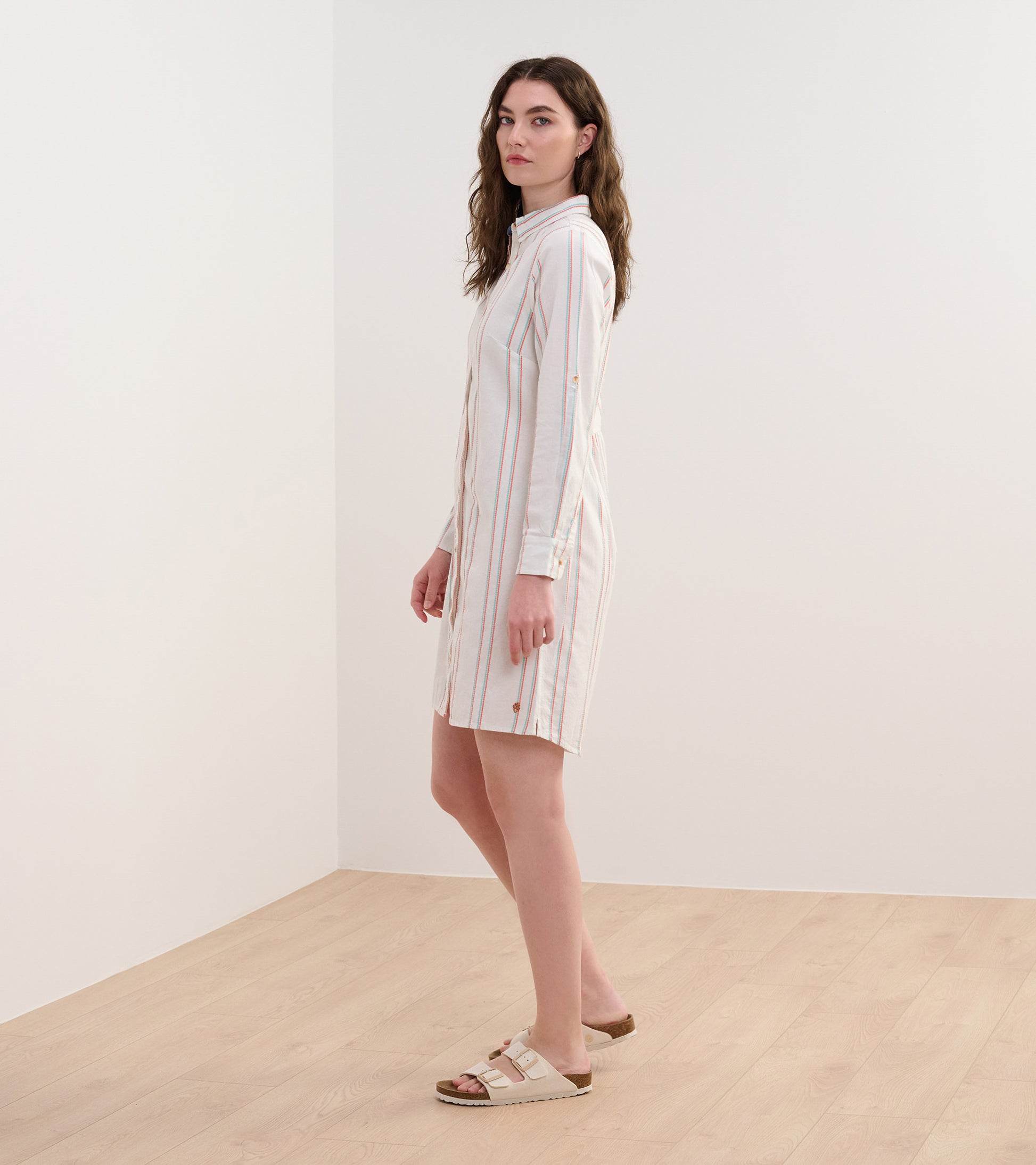 Peach and white striped shirt dress with long sleeves and a button-down front, styled with casual sandals.