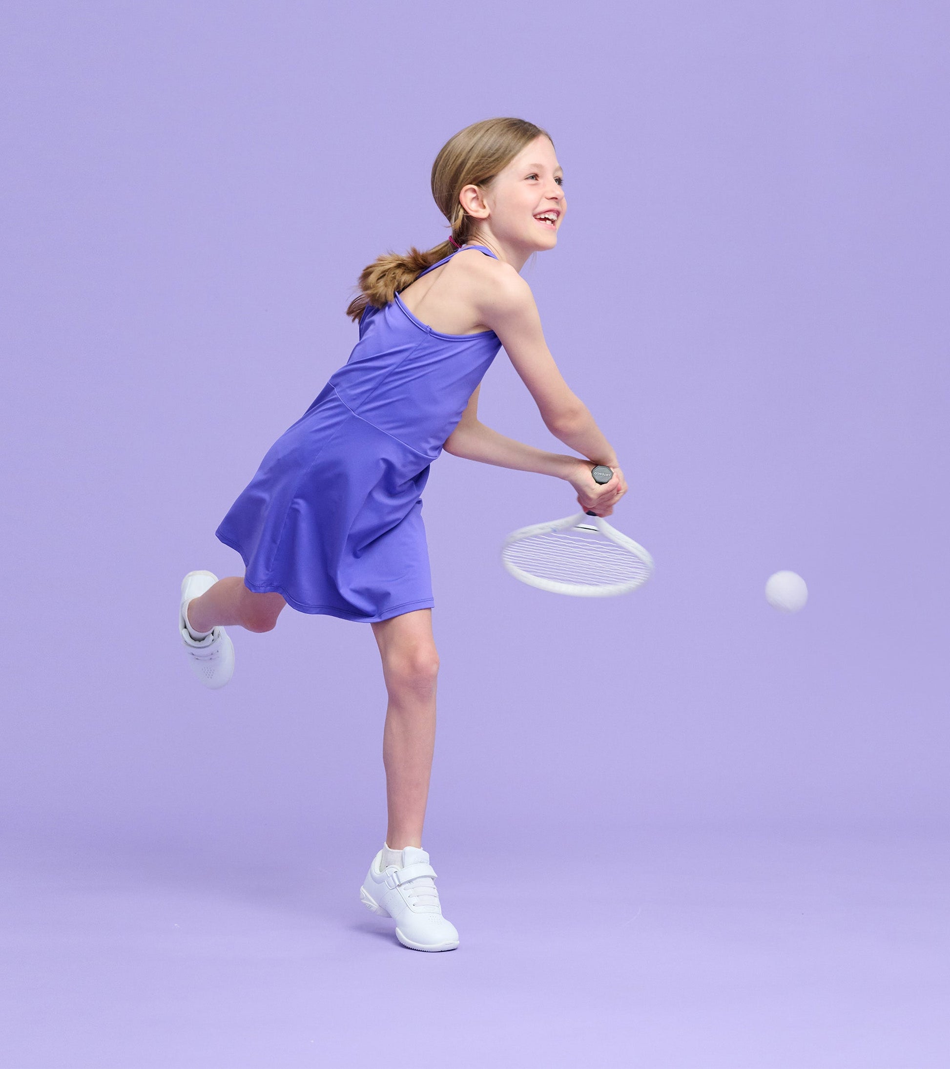 Purple A-line dress on a girl playing tennis, featuring a sleeveless design and a playful, active look.