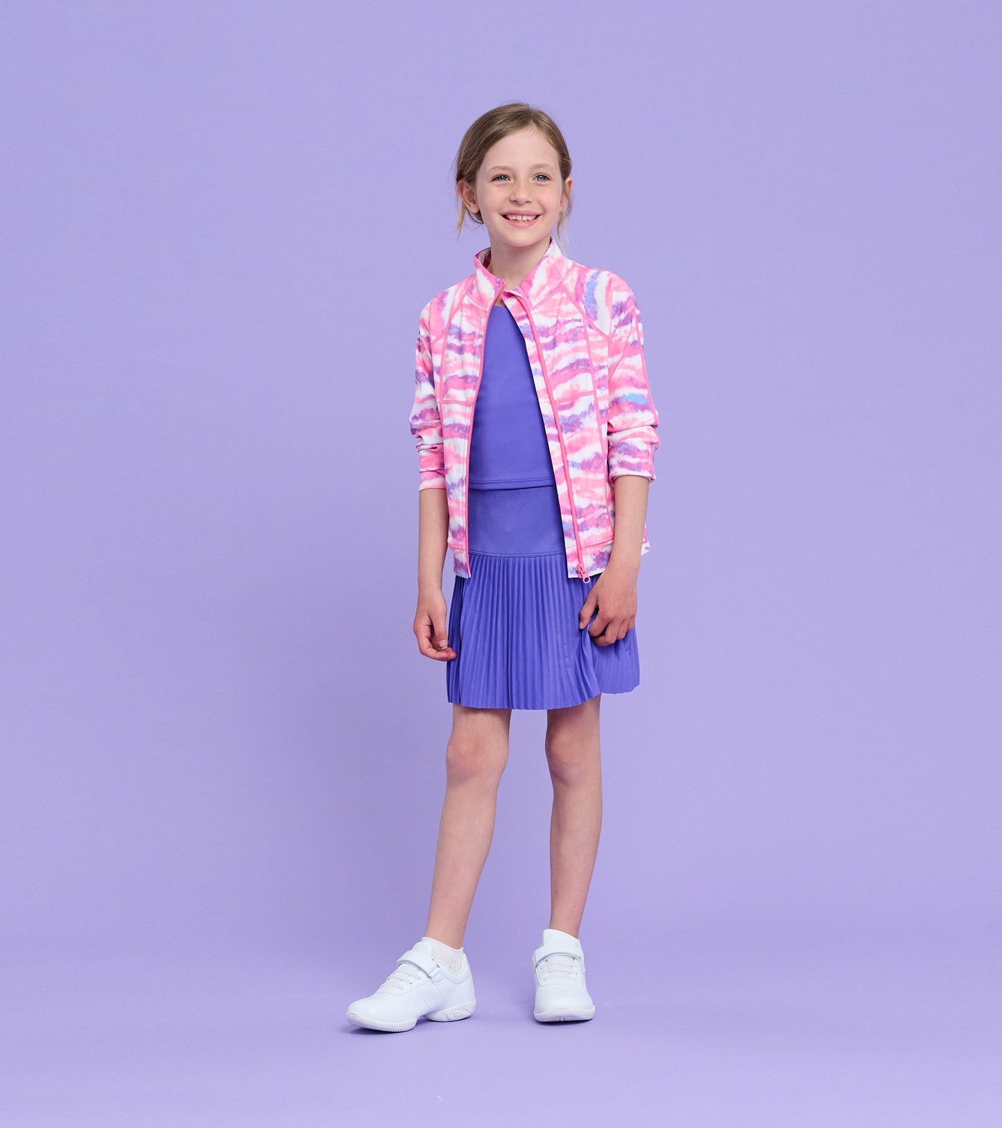 Purple sporty skort with pleated design, paired with a matching top and a colorful jacket, worn by a smiling girl.