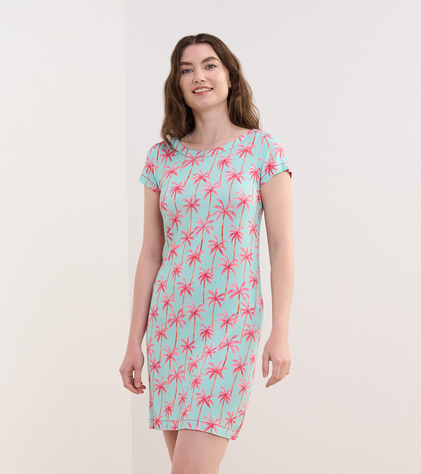 Short-sleeve dress featuring a light blue background with pink palm tree prints, ideal for casual summer wear.