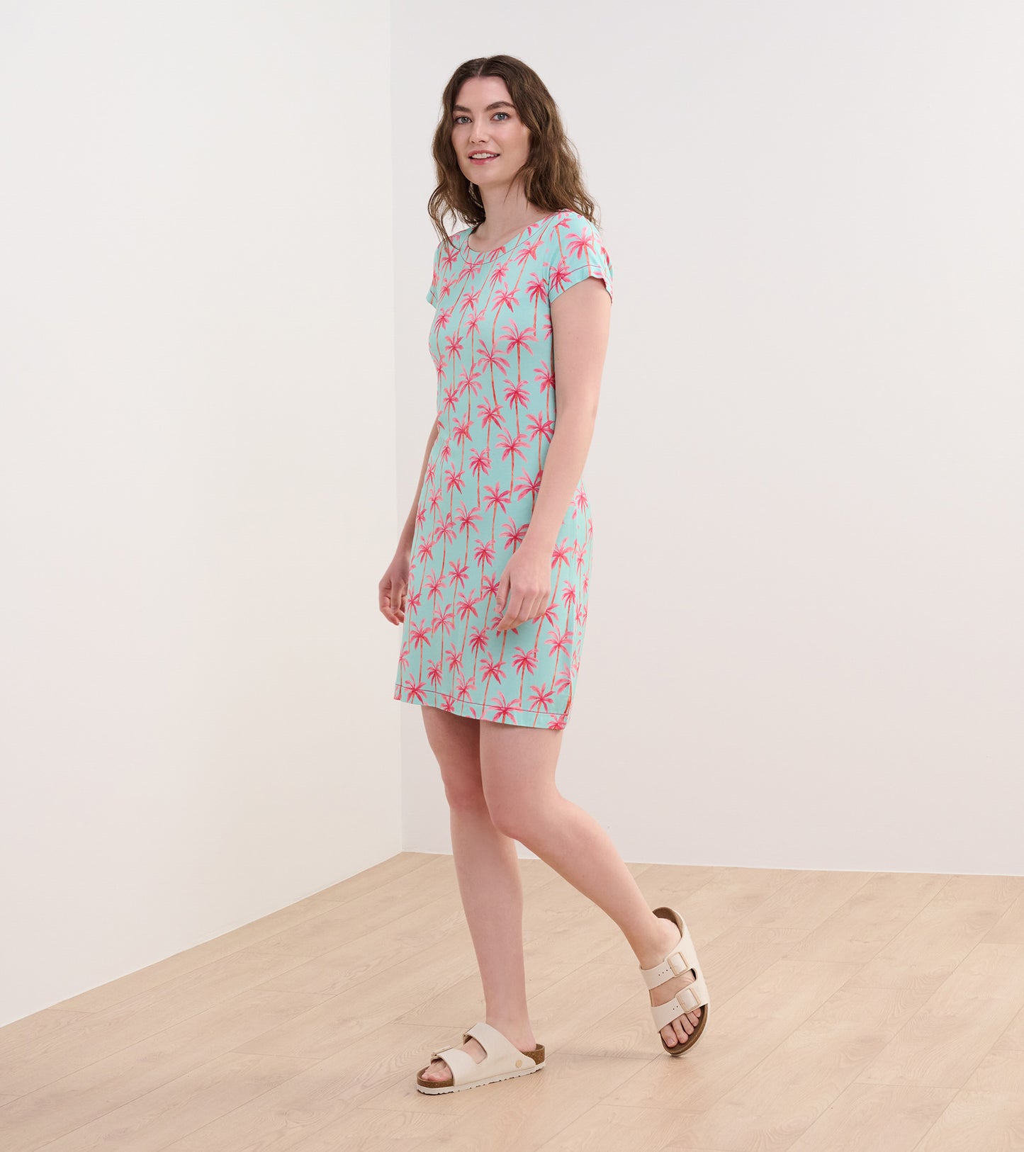 Short-sleeve dress featuring a light blue background with pink palm tree prints, ideal for casual summer wear.