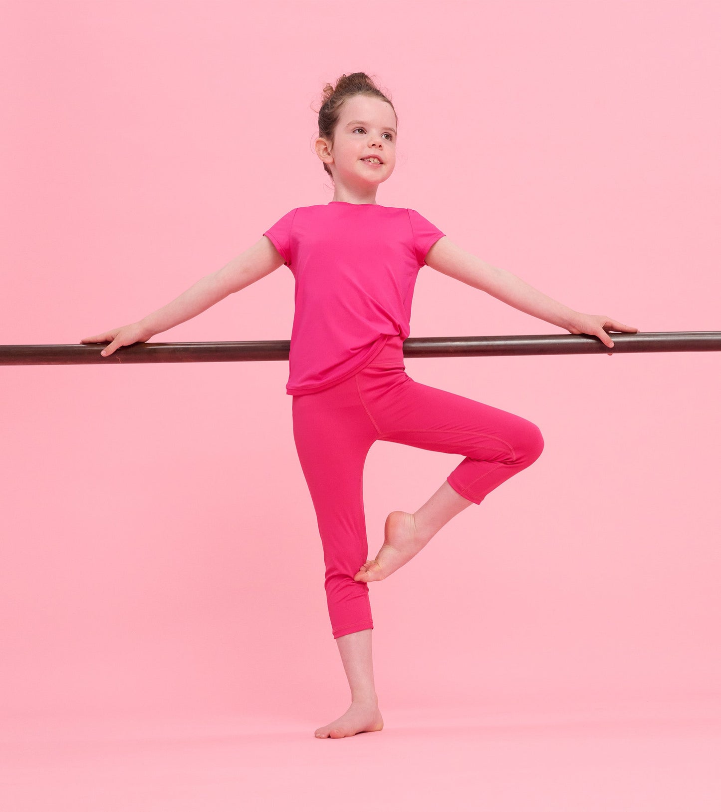 Bright pink short-sleeve t-shirt with mesh trim, styled for active wear, paired with matching pink leggings.