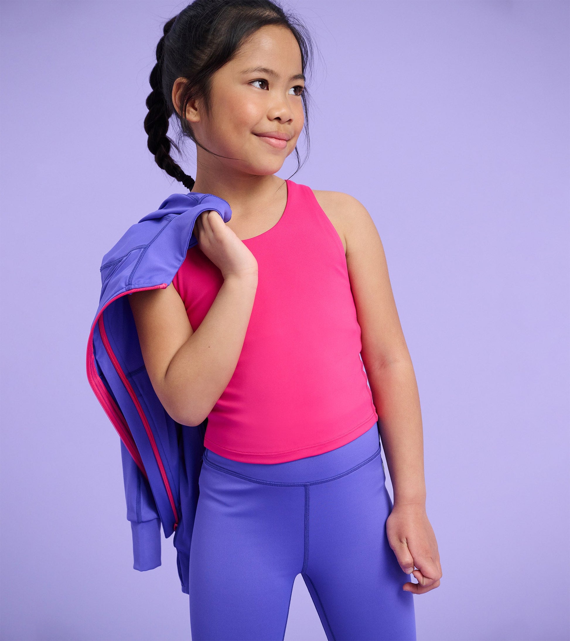 Bright pink tank top on a girl, paired with purple leggings, set against a light purple background.