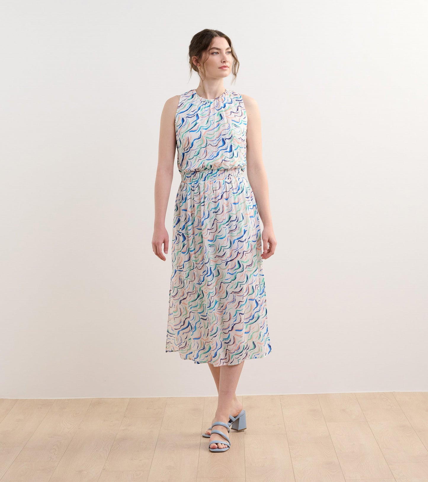 Sleeveless column dress featuring wavy stripes in pastel colors, with an elastic waist and a flowy silhouette.