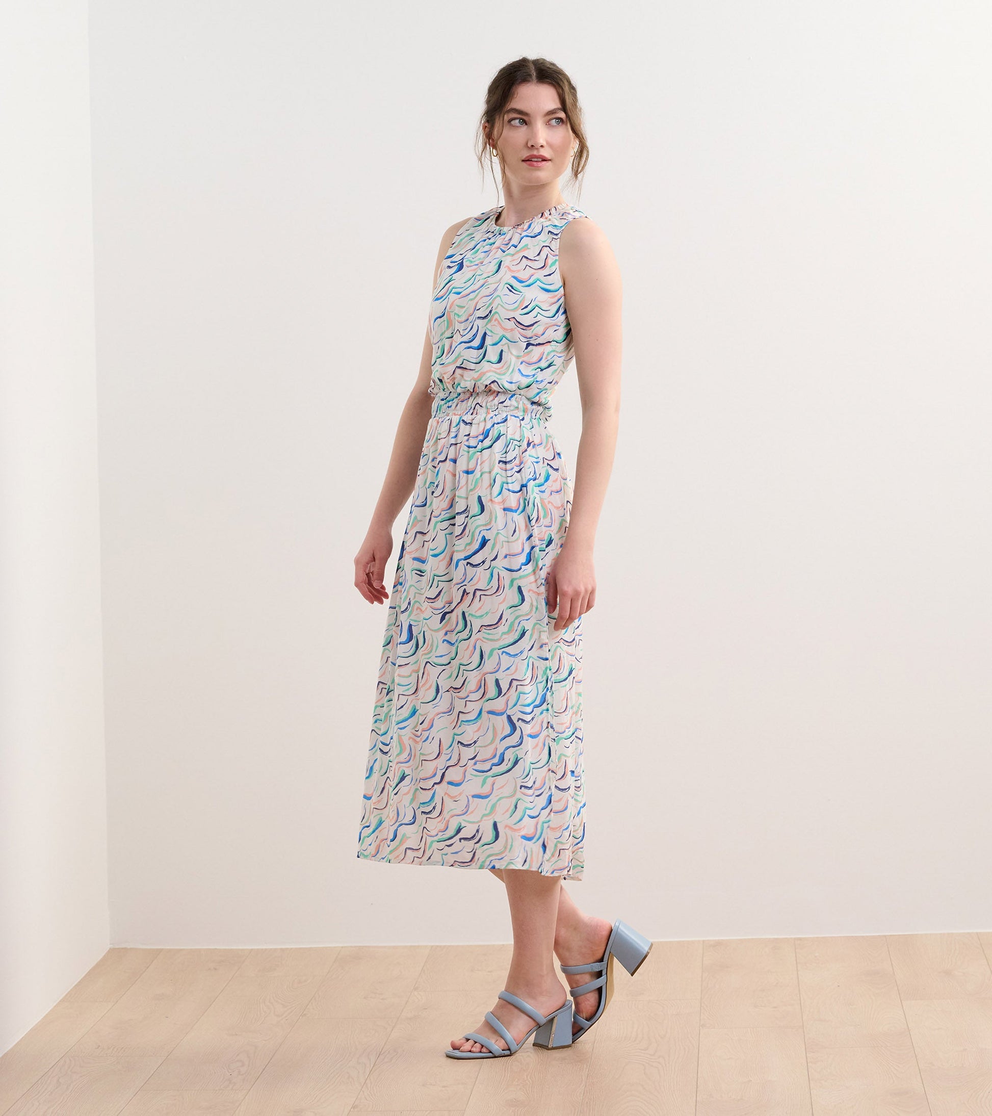 Sleeveless column dress featuring wavy stripes in pastel colors, cinched waist, and a flowy silhouette.