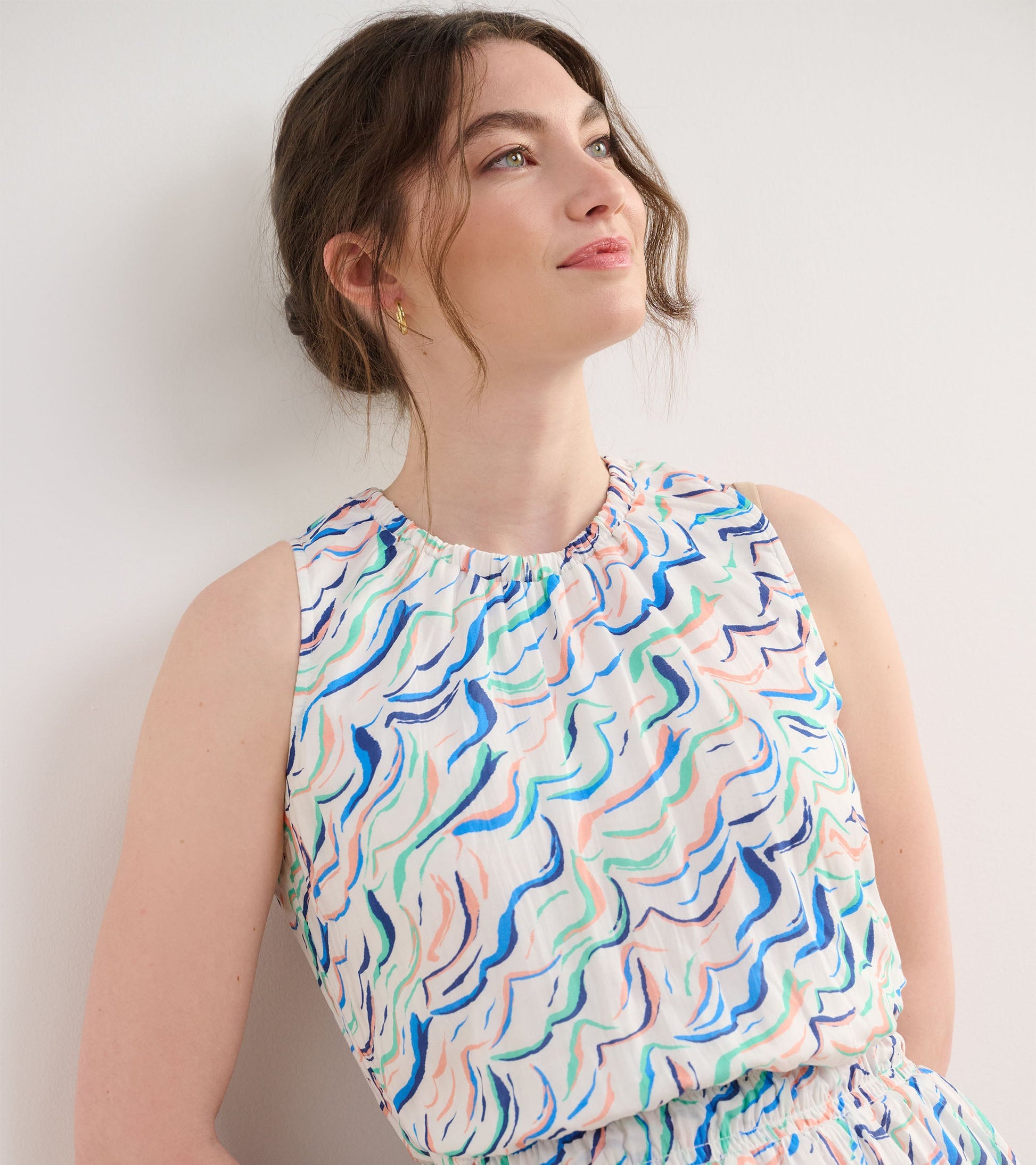 Sleeveless dress featuring a wavy stripe pattern in pastel colors, with a gathered neckline and elastic waist.