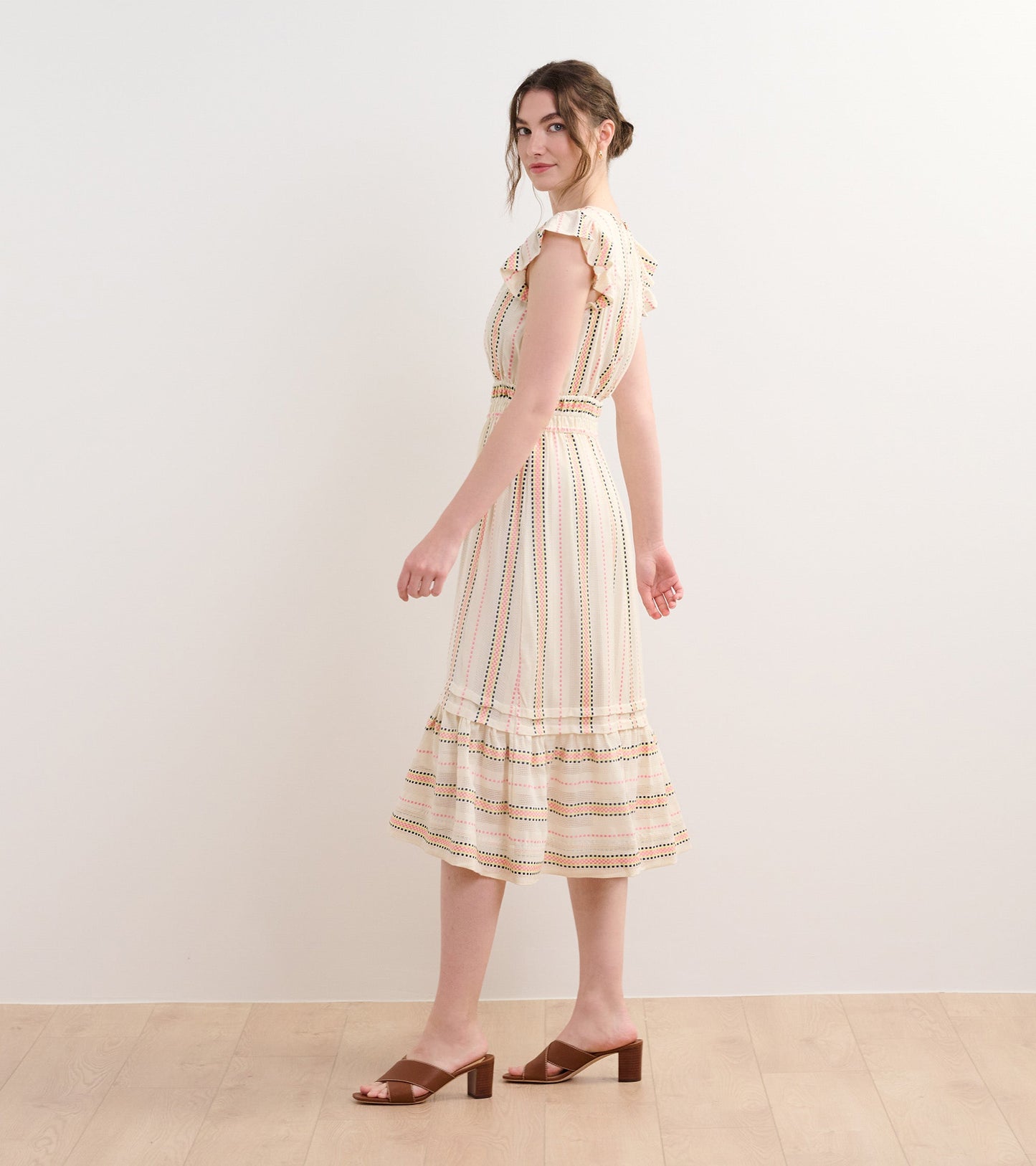 Cream midi dress with ribbon weave stripes, ruffled sleeves, and a flared hem, styled with brown block-heeled sandals.