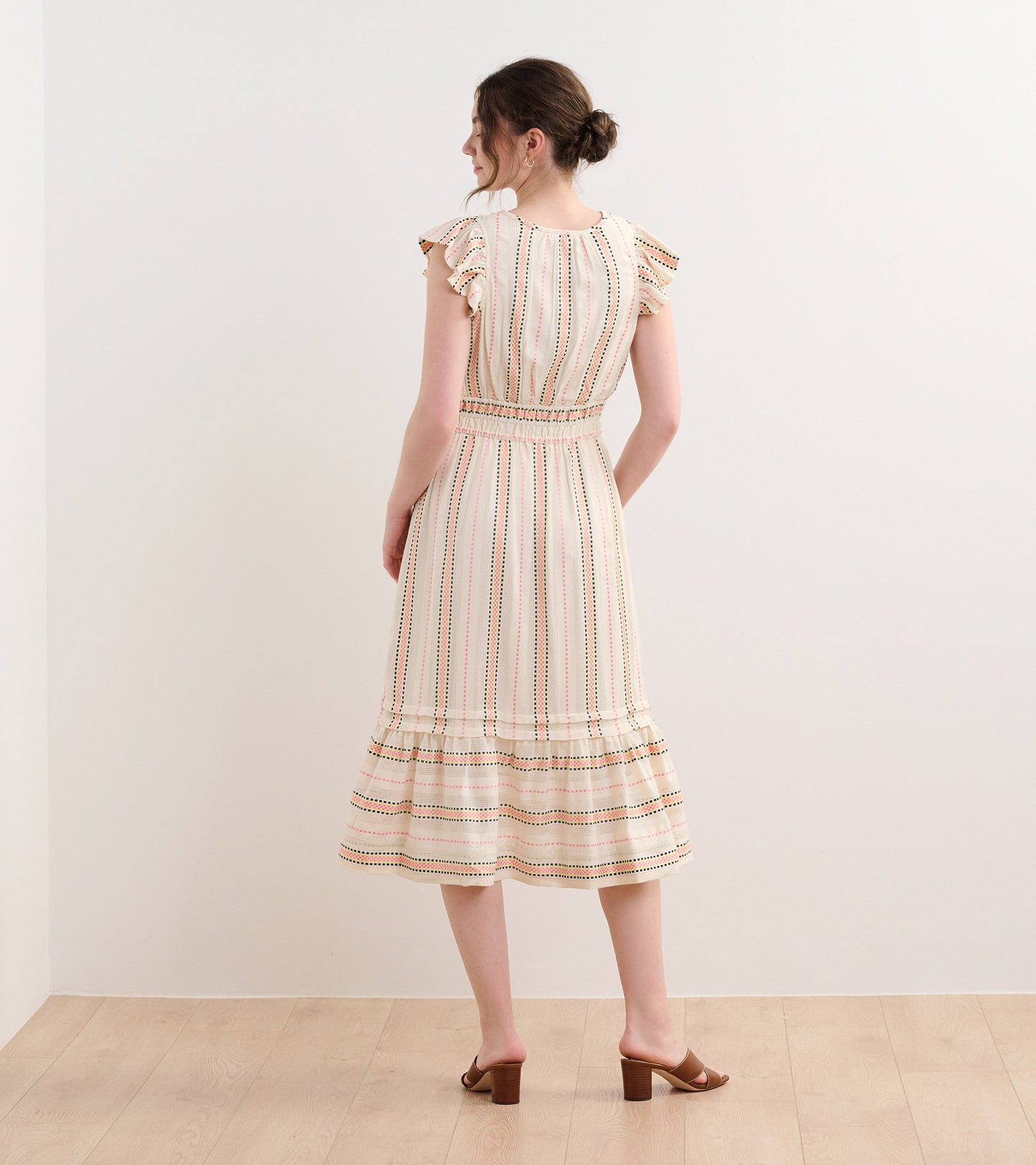 Back view of a midi dress featuring ribbon weave stripes, ruffled sleeves, and a flared hem.