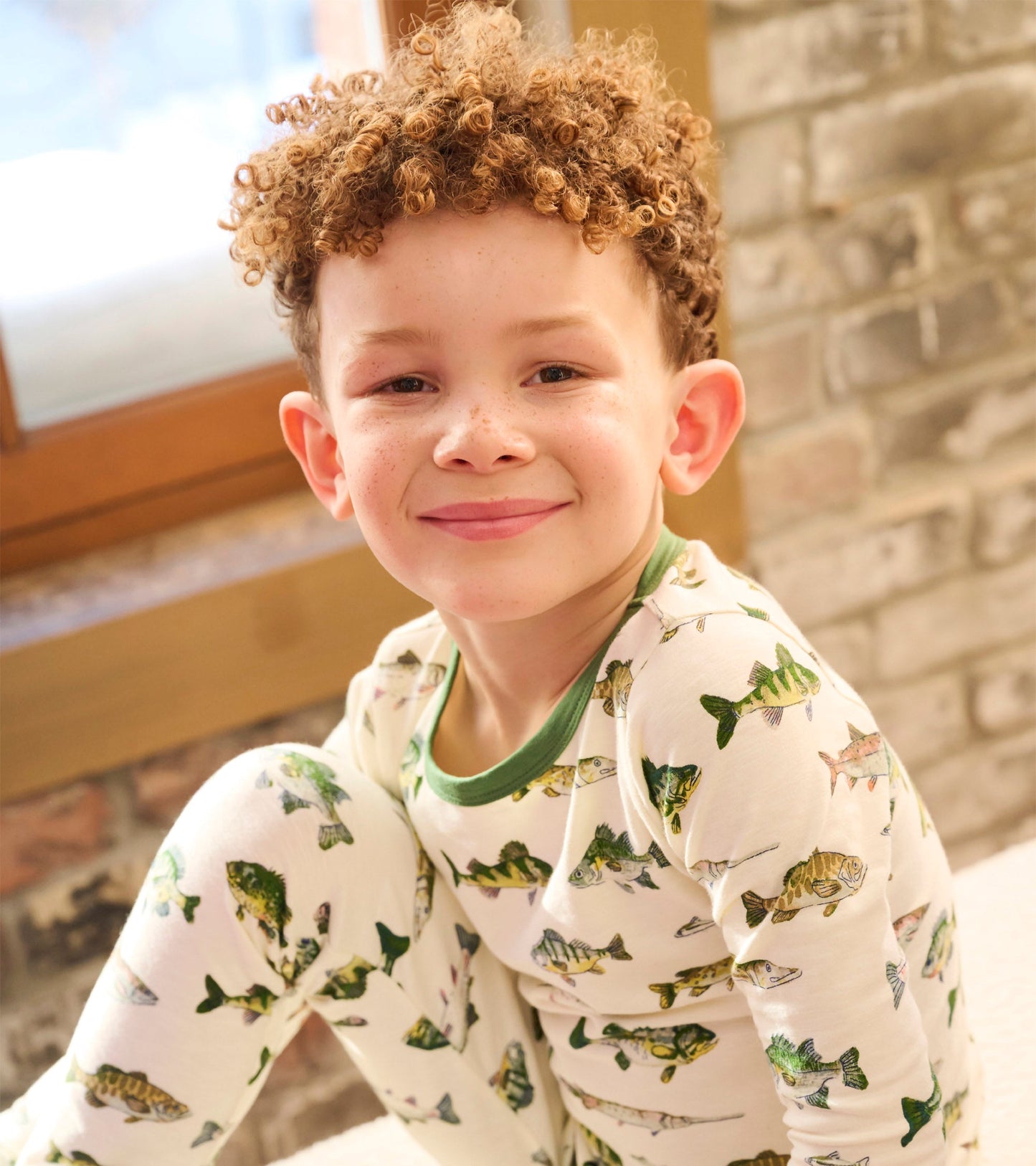 Boys' pajama set featuring a white base with colorful fish patterns and green trim, ideal for comfortable sleepwear.