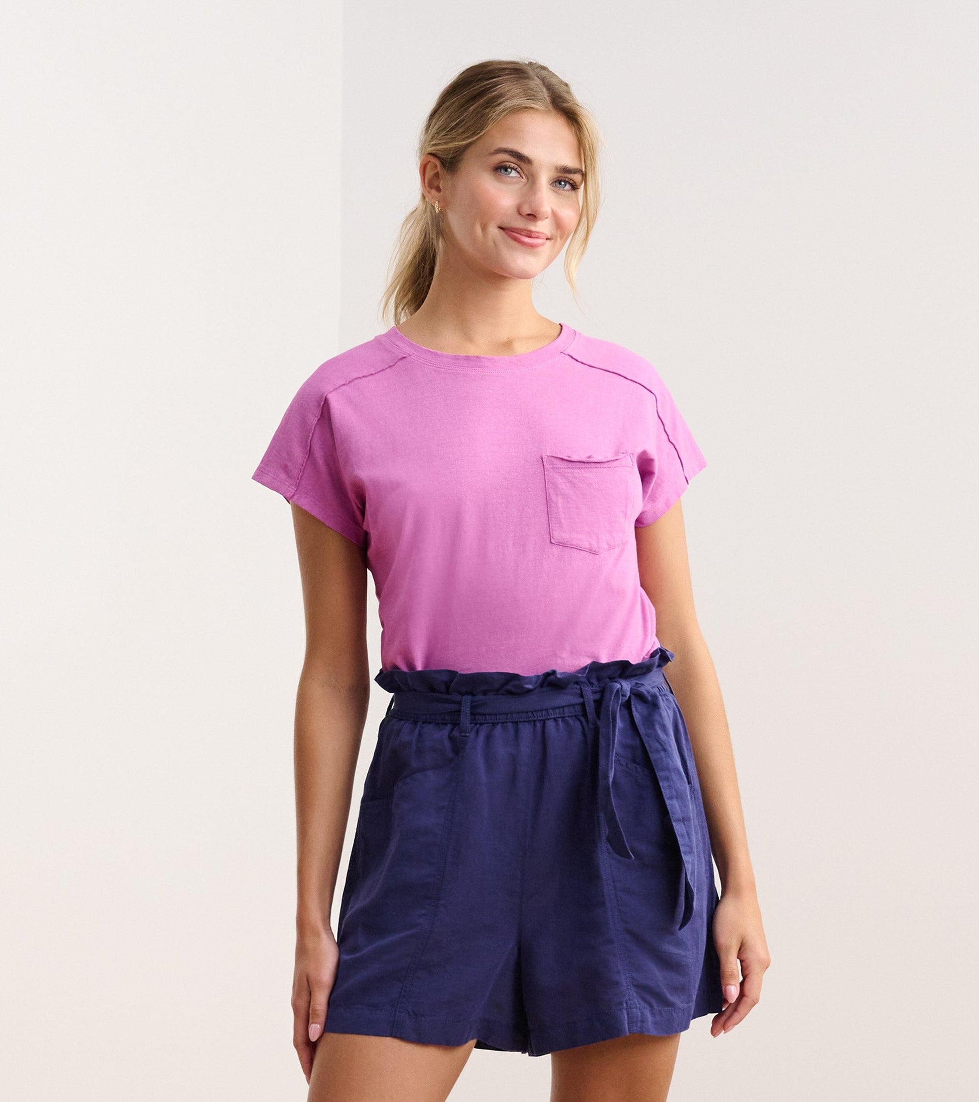 Slouchy orchid tee with short sleeves and a chest pocket, paired with navy shorts.