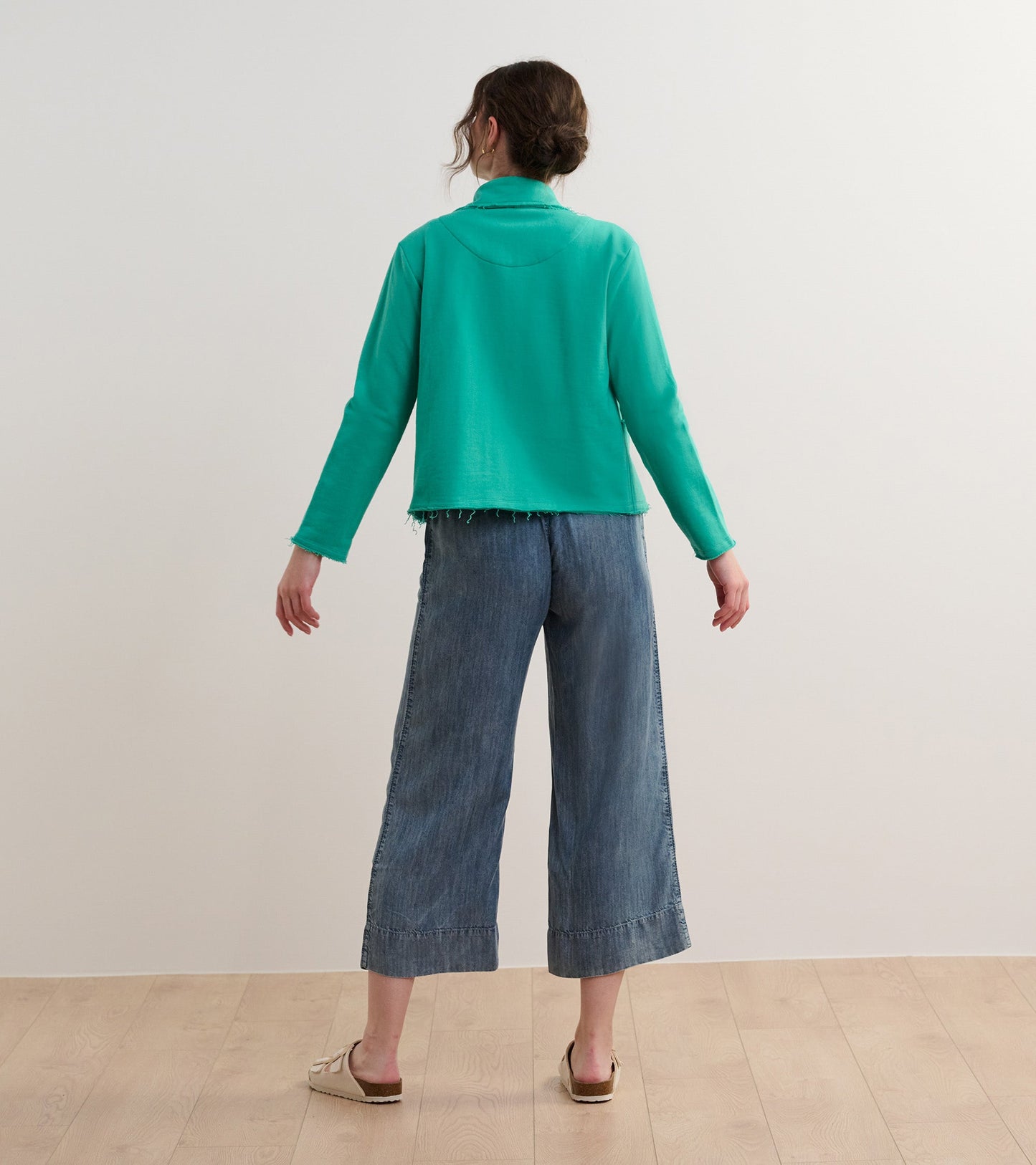 Sea green preppy blazer with a relaxed fit and frayed hem, worn with wide-leg denim pants, viewed from the back.