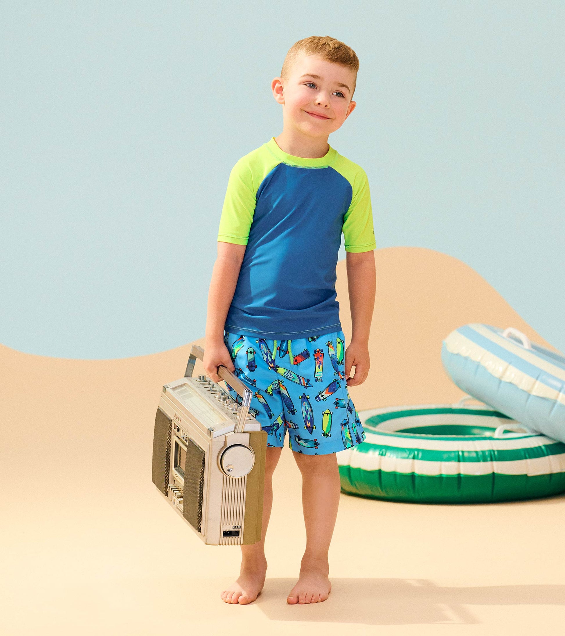 Short sleeve rashguard in blue with neon green accents, paired with colorful patterned swim shorts, ideal for beachwear.