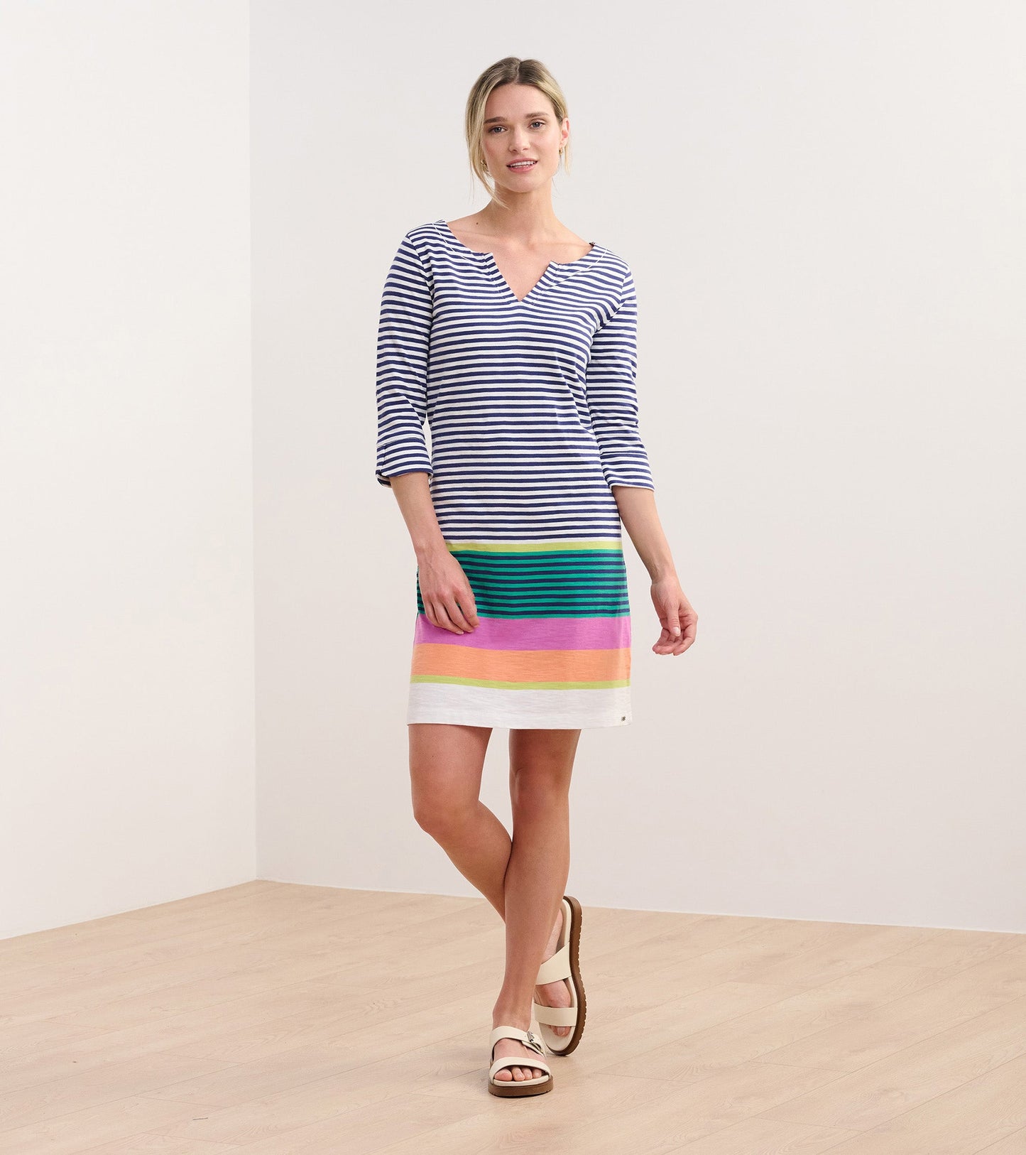 Striped dress with a V-neck, featuring a colorful horizontal stripe pattern at the hem, suitable for casual wear.