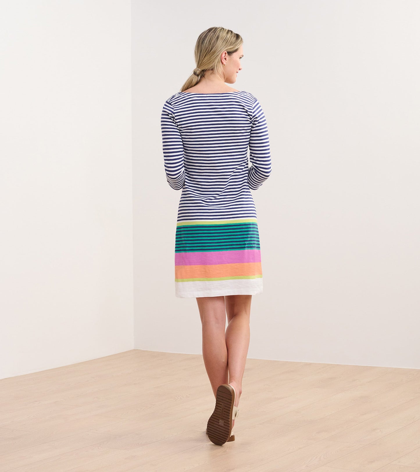 Striped dress featuring navy and white stripes with a colorful striped hem in pink, green, and yellow. Back view.