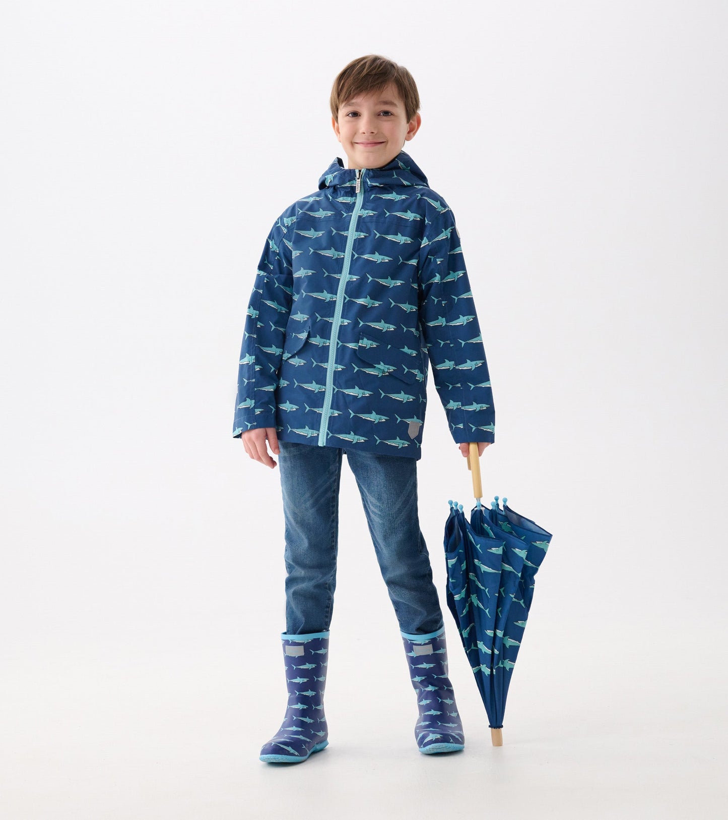 Lightweight navy rain jacket with shark pattern, hood, and front zipper, paired with blue jeans and matching rain boots.